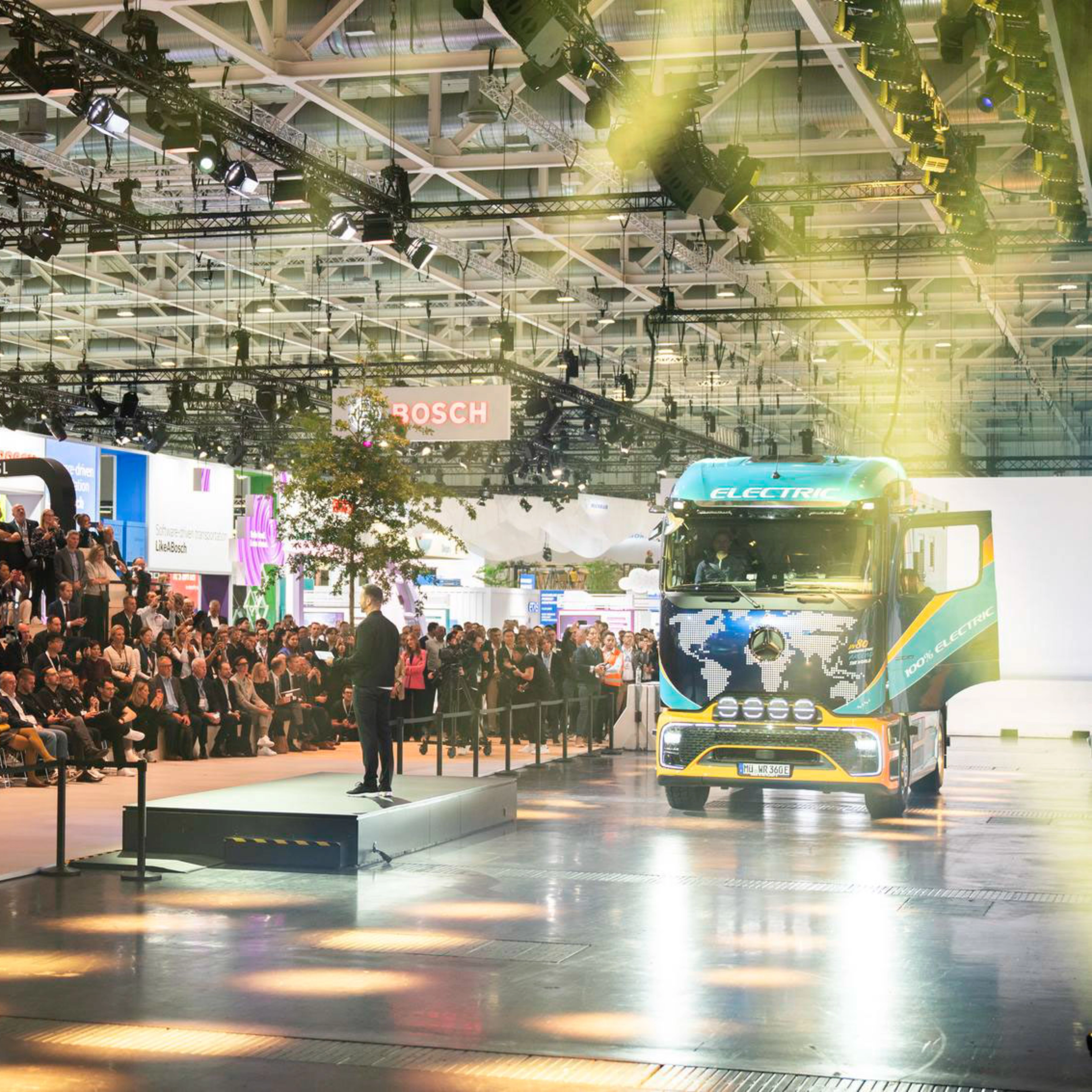 Lkw fährt in einer Messehalle an einem großen Publikum vorbei.