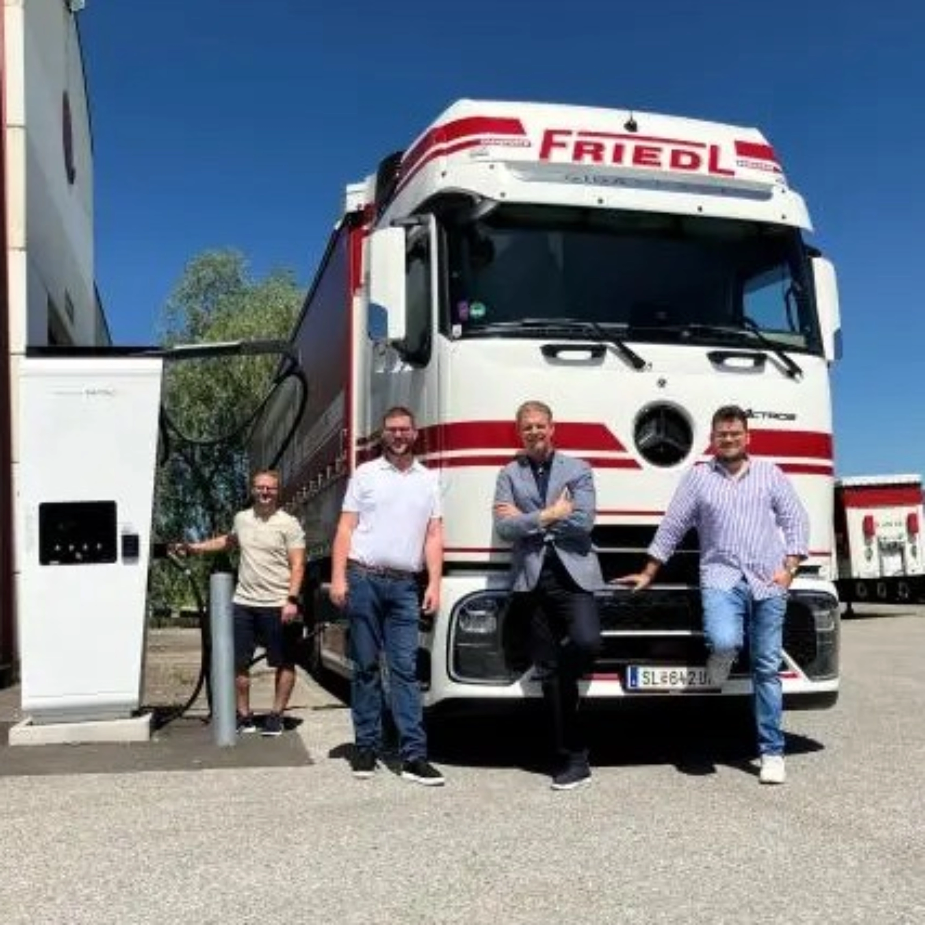 Vier Männer stehen vor einem weißen Frigel Lkw.