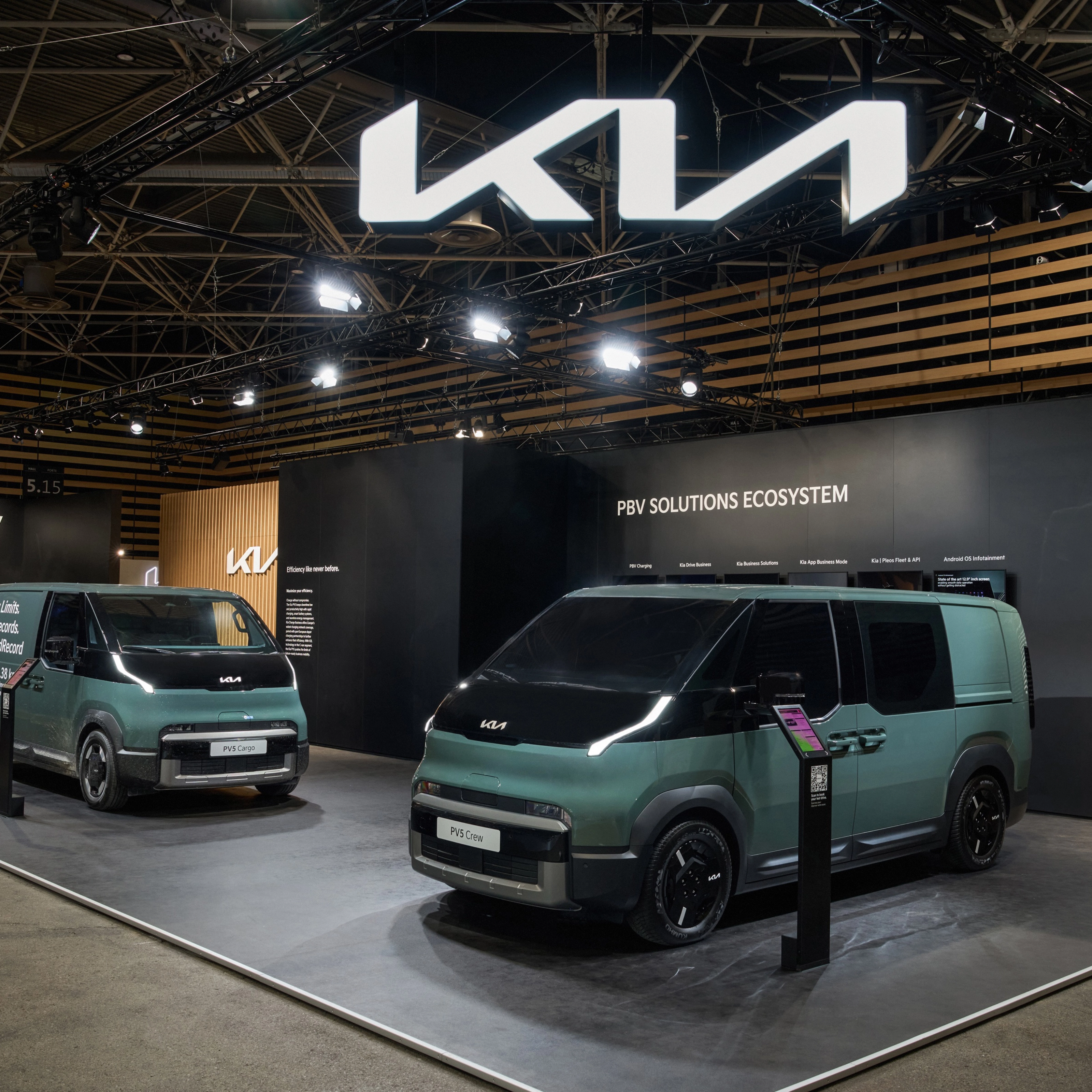 Zwei grüne Kia PBV Transporter stehen auf einem Messestand mit Kia-Logo.