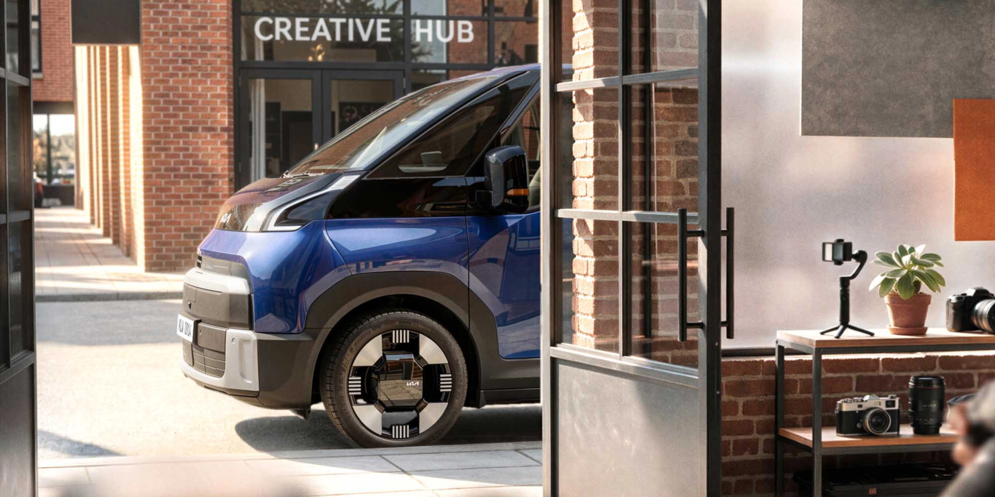 Blauer Kia PV7 vor einem Creative Hub.