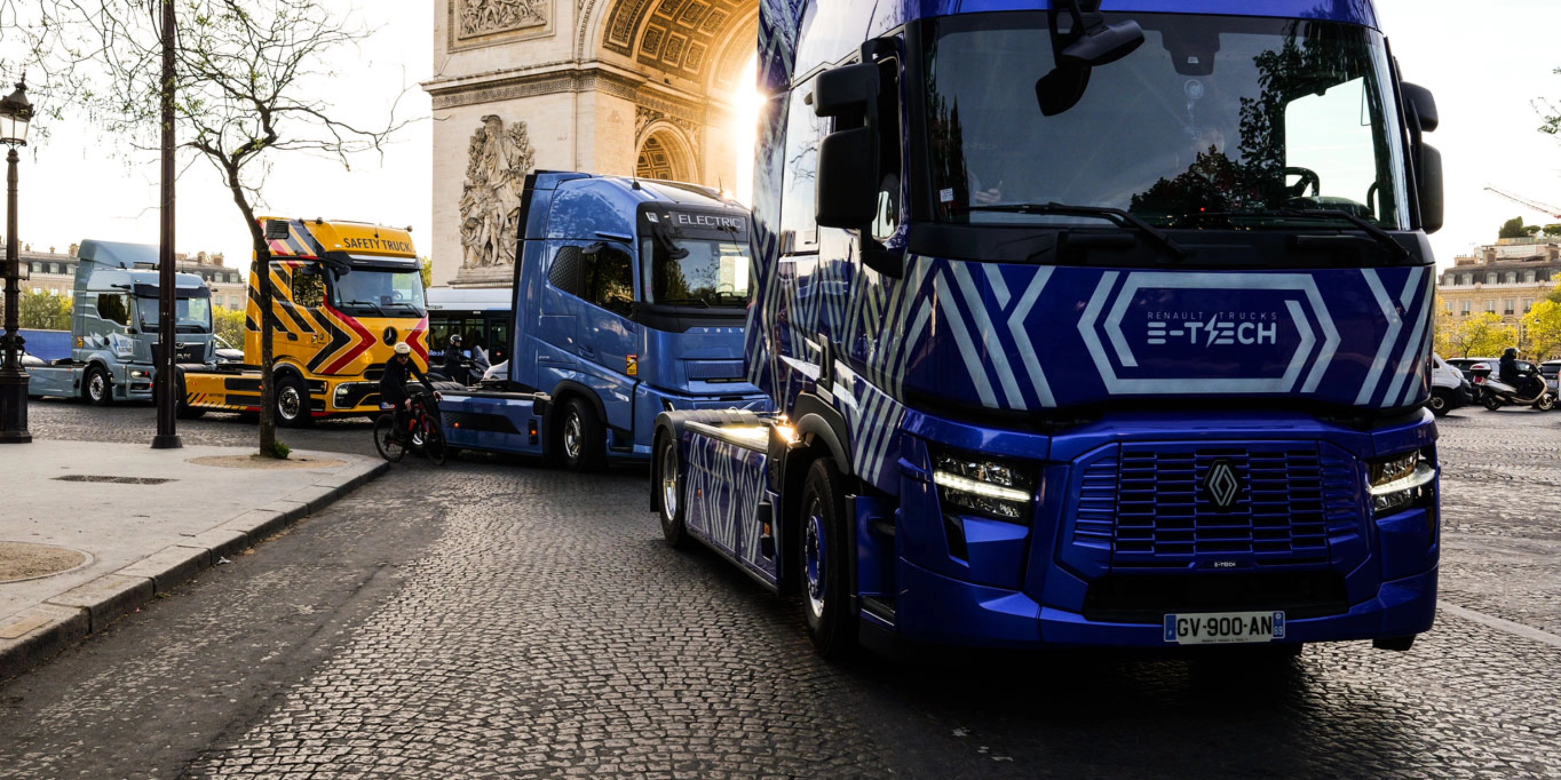 Blue electric truck driving past the Arc de Triomphe in Paris.