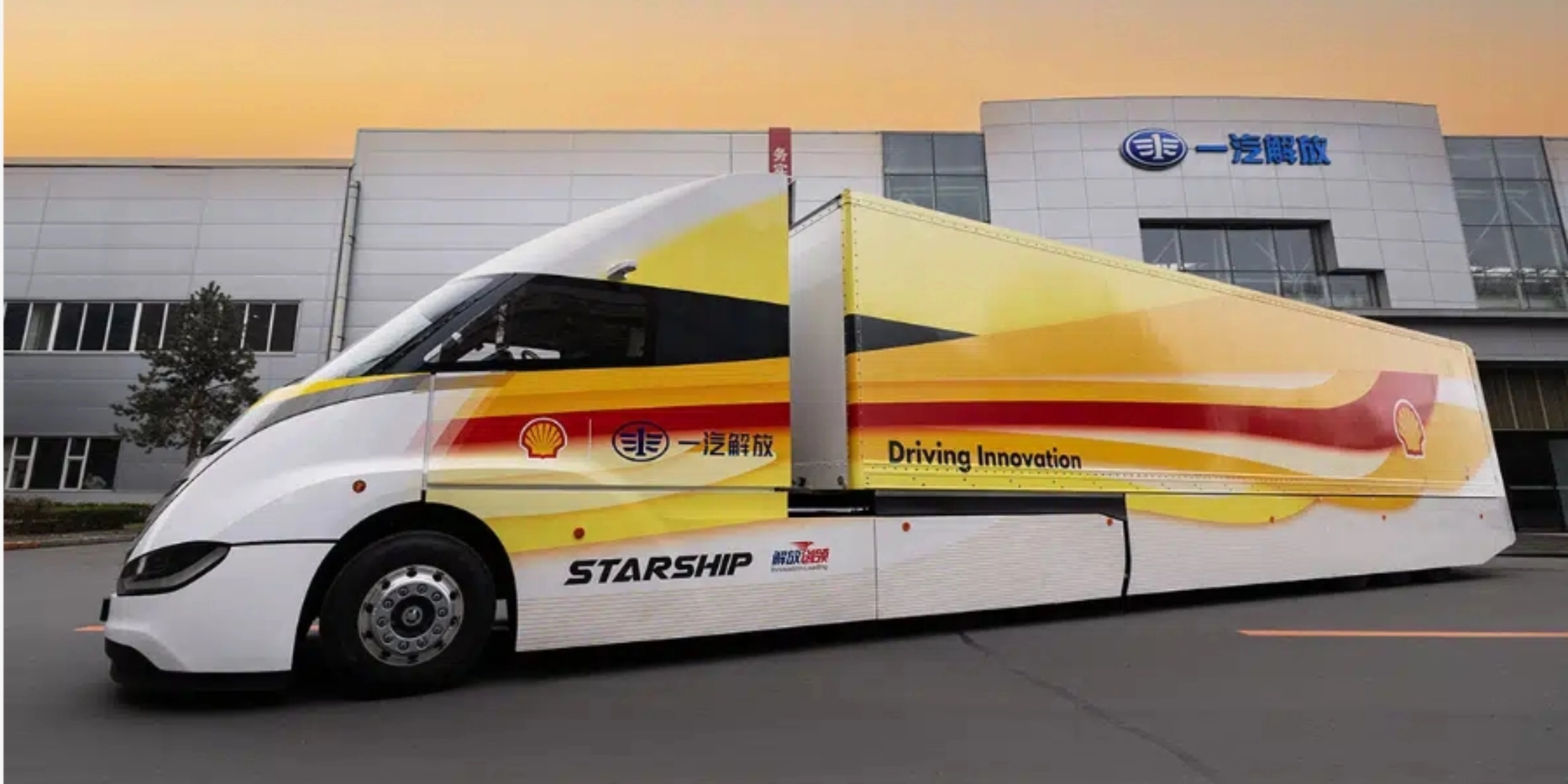 Weißer STARSHIP-Bus mit roten und gelben Streifen vor einem Industriegebäude bei Sonnenuntergang.