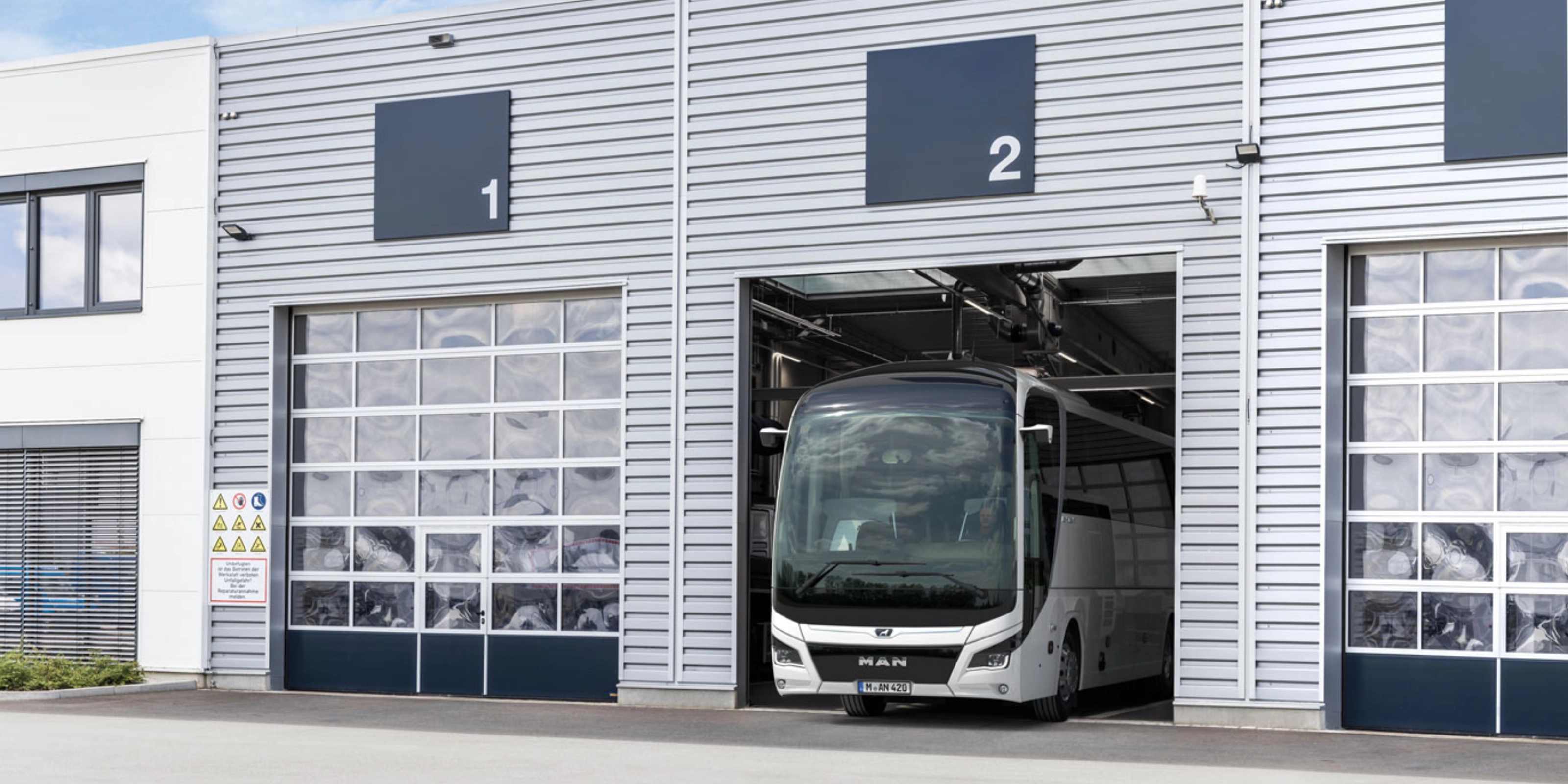 Ein Bus steht in einer nummerierten Garage eines modernen Betriebsgebäudes.