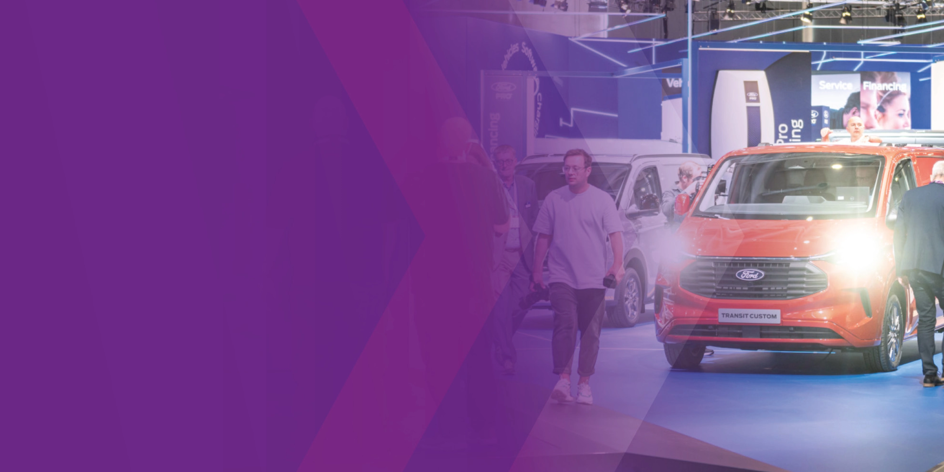 Visitors walking past a Ford Transit Custom at an IAA trade fair booth.