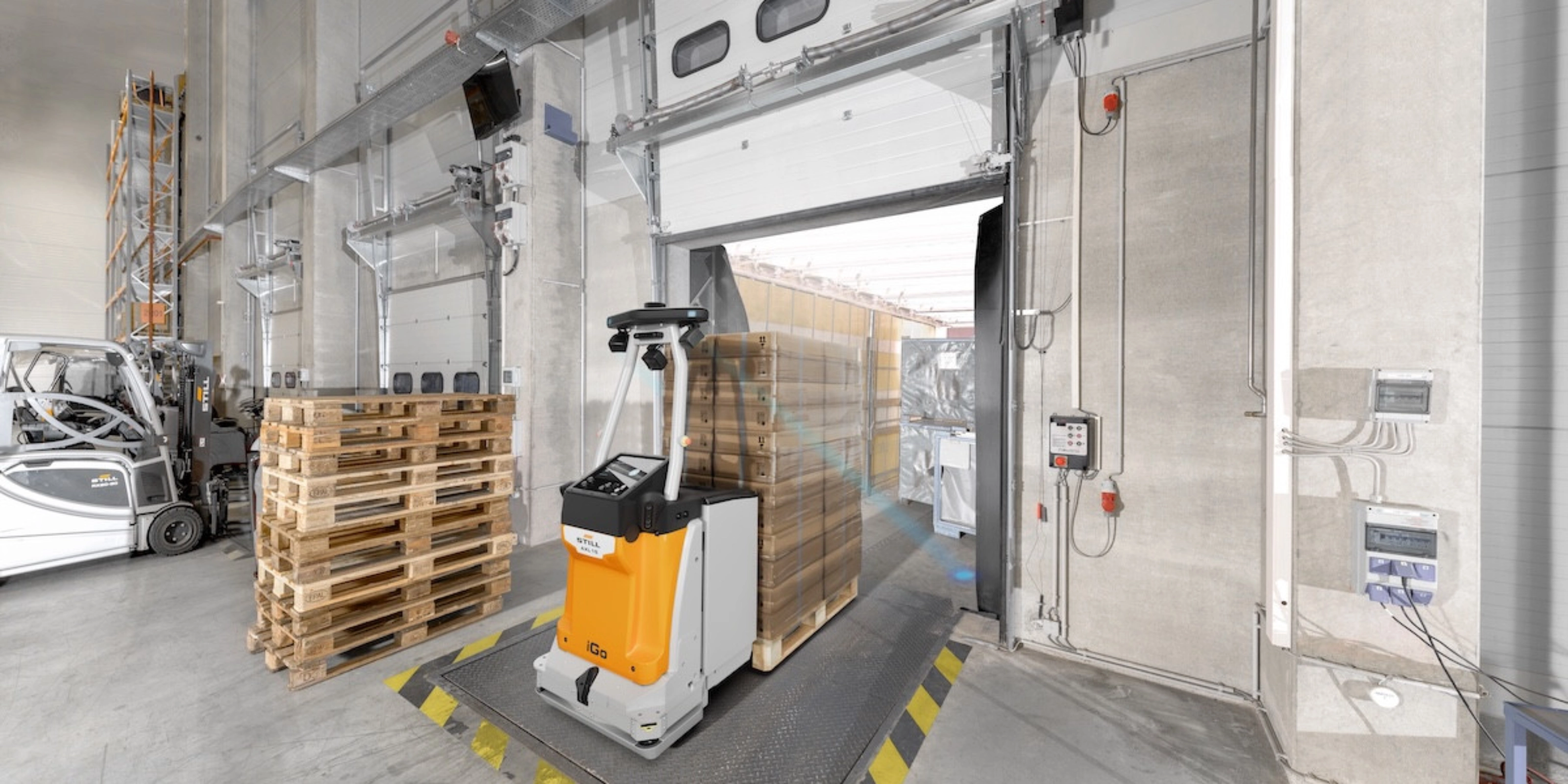 Autonomous mobile robot transporting goods at an industrial loading gate.