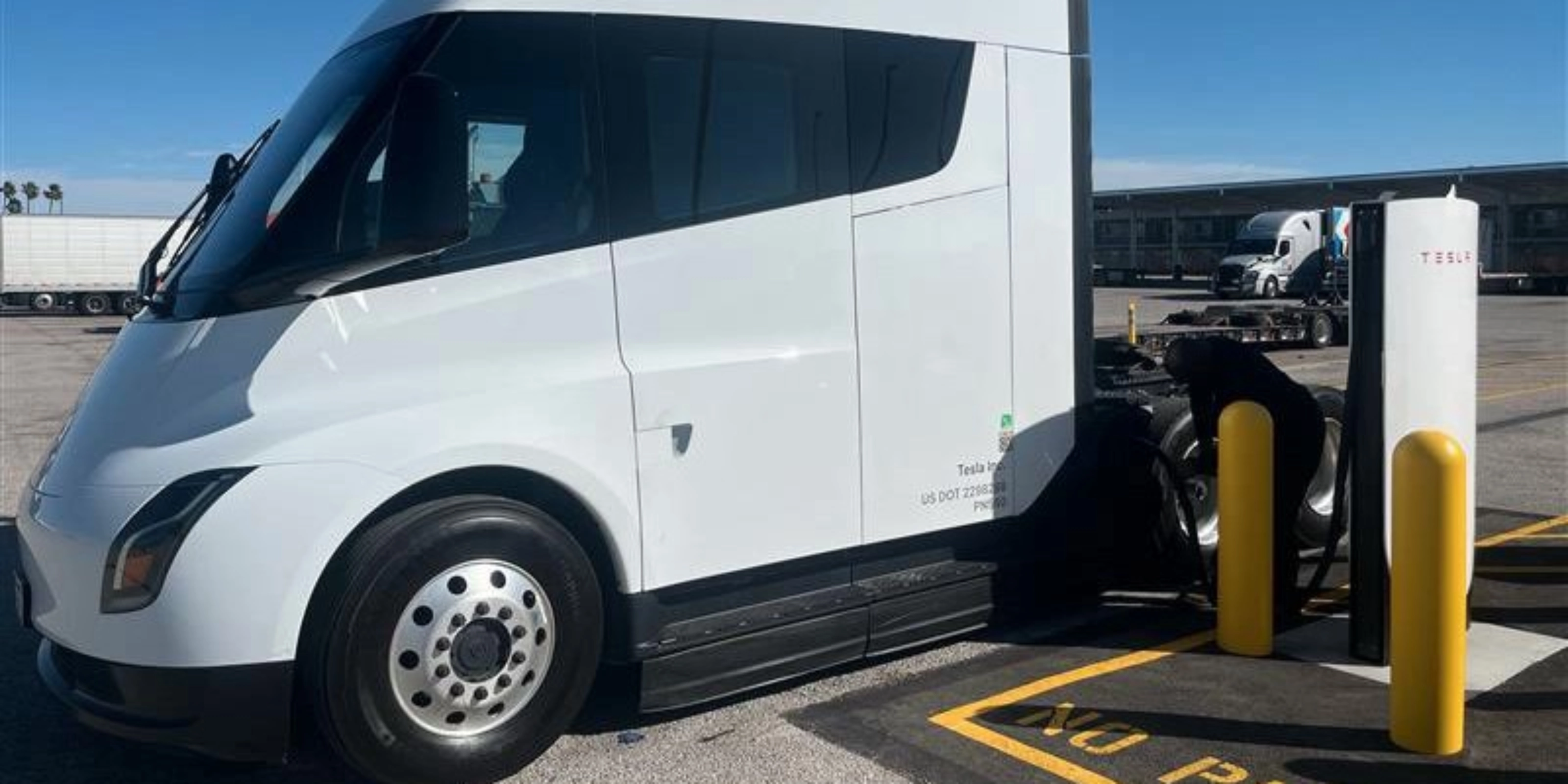 White Tesla Semi charging at a Tesla charging station.