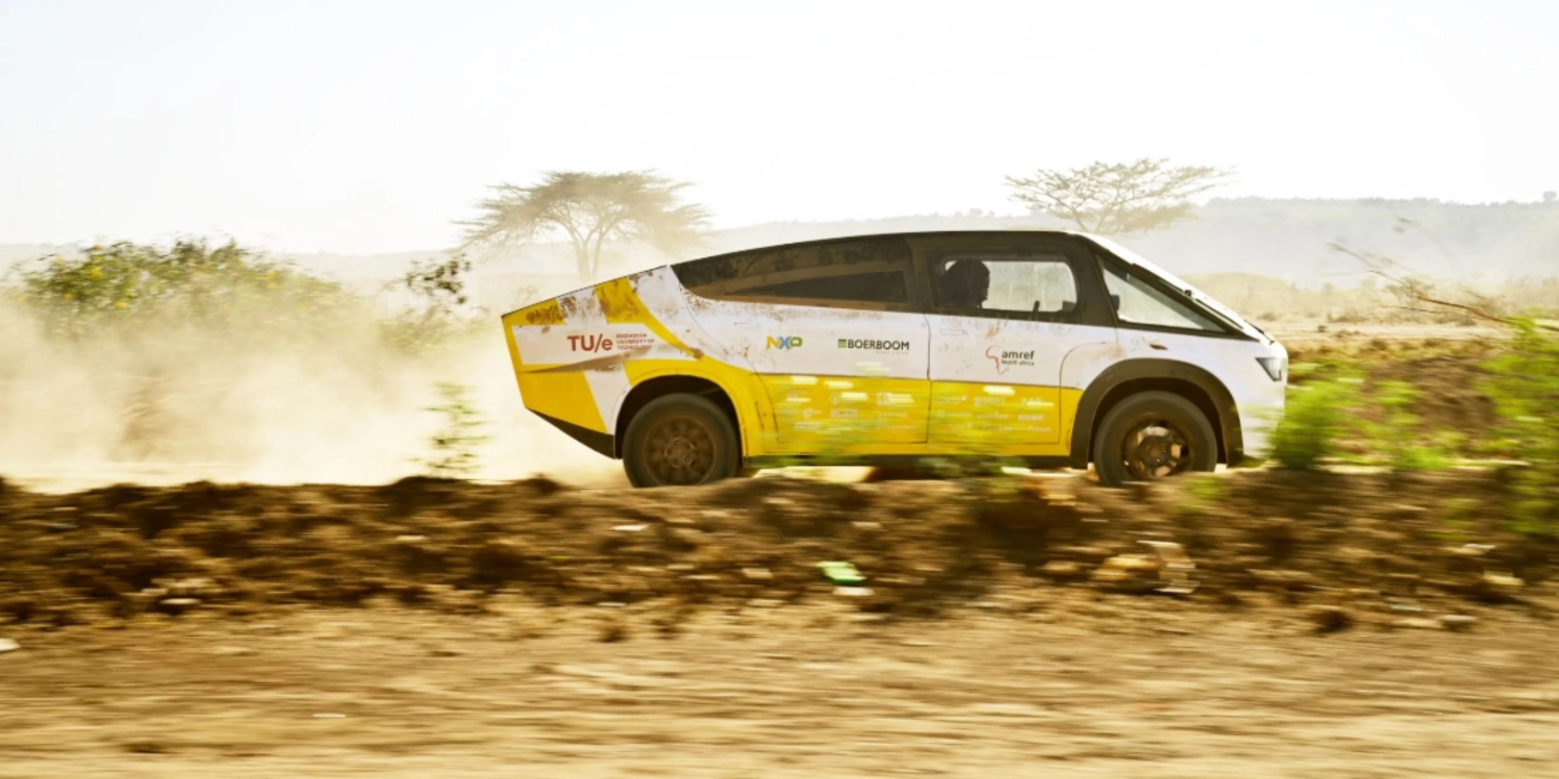 Fahrzeug des Solar Team Eindhoven fährt auf einer staubigen unbefestigten Straße.