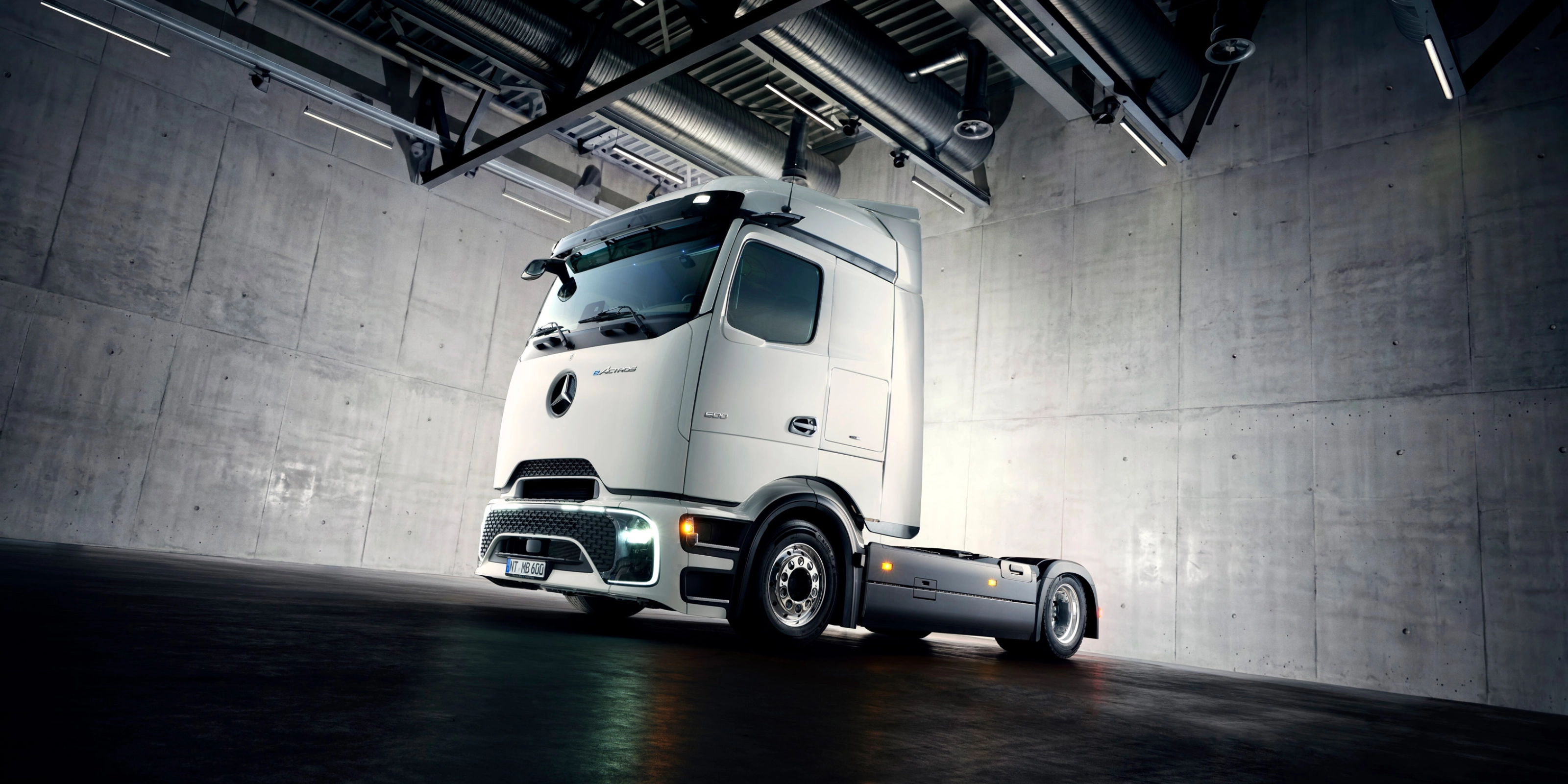 Autonomes Lkw-Fahrgestell in Industriehalle unter Scheinwerfern.