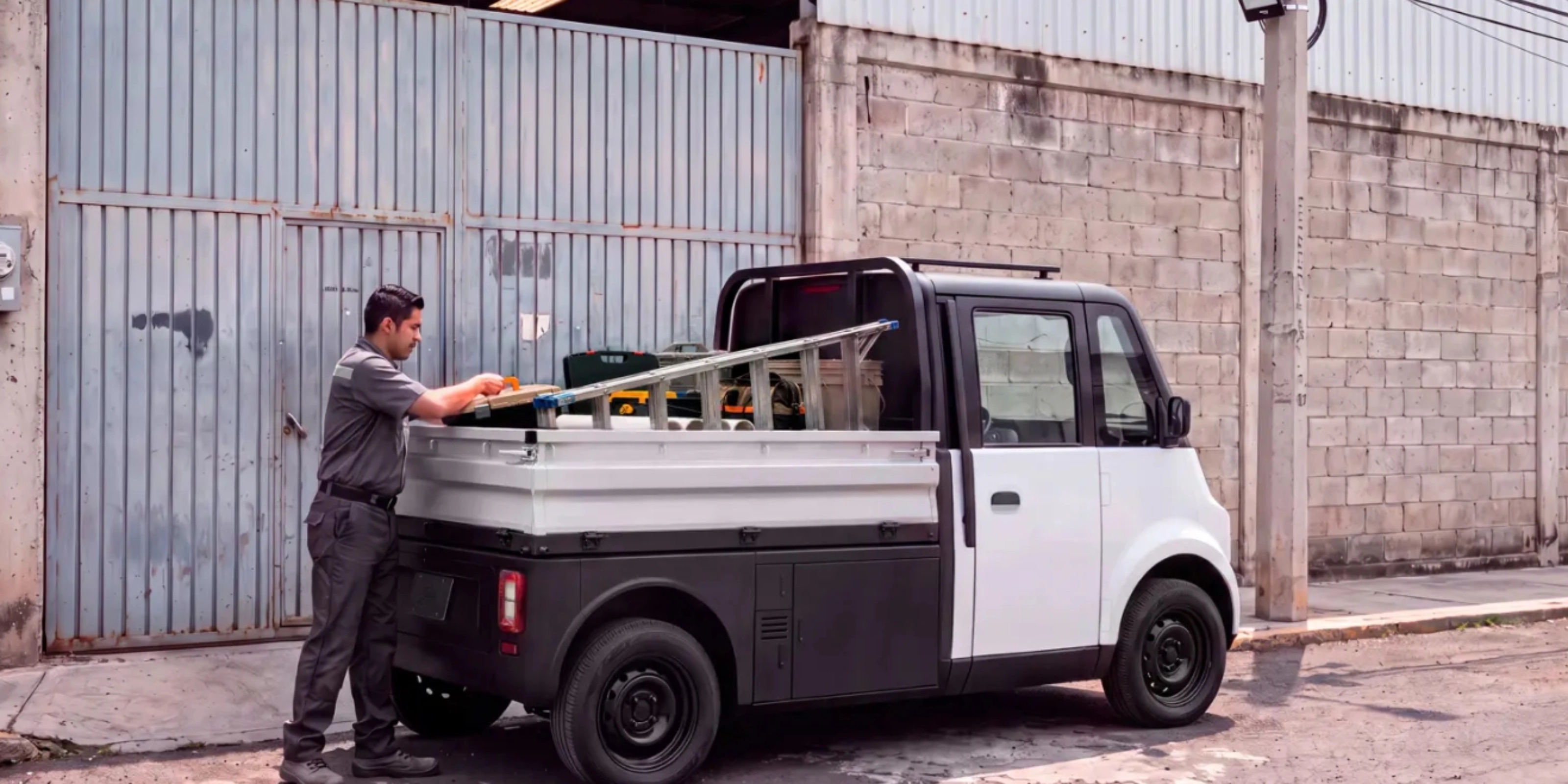 Compact Olinia utility vehicle being loaded at the roadside.