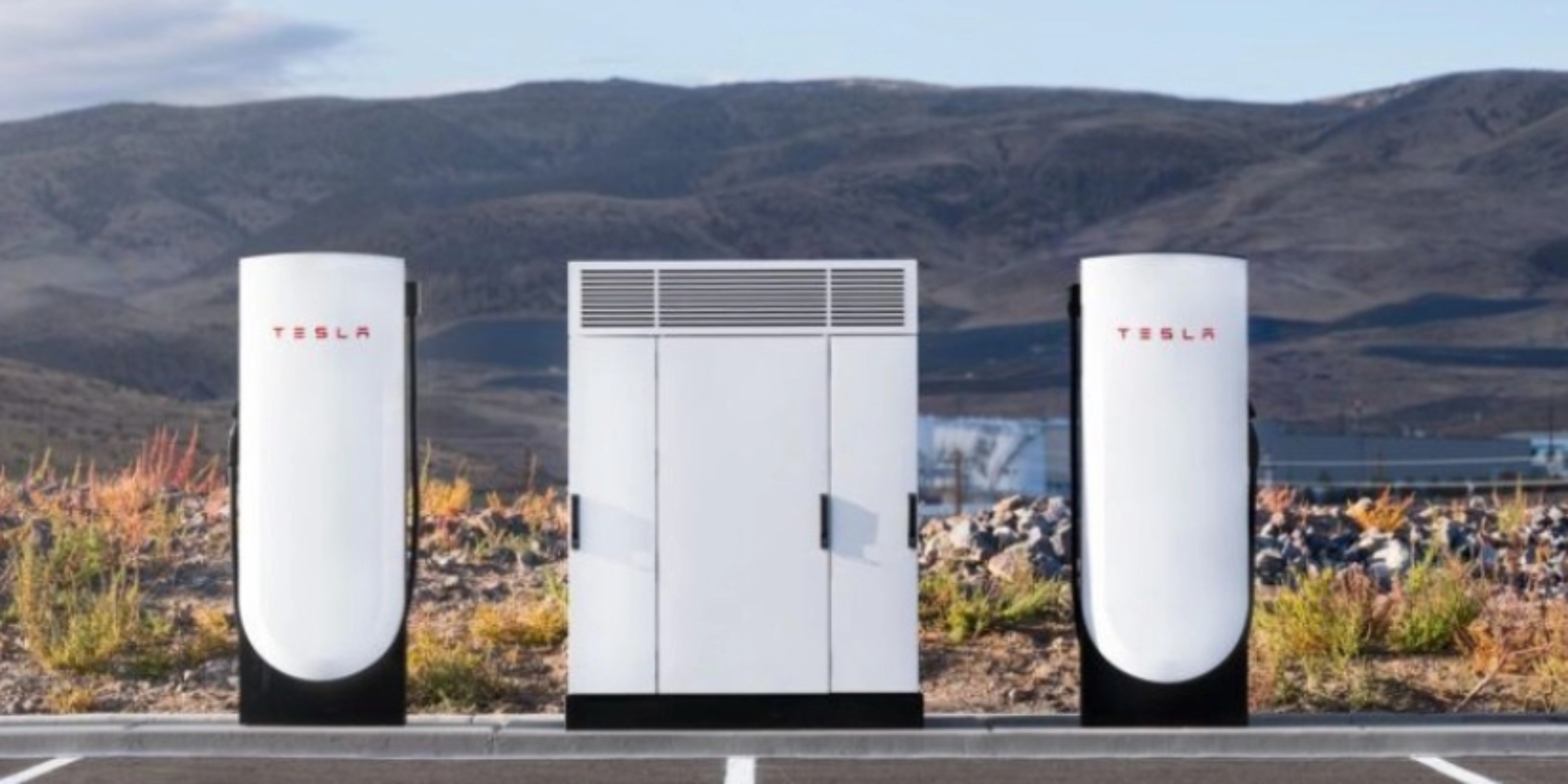 Tesla Supercharger station with two charging posts and a central power unit in a parking lot.