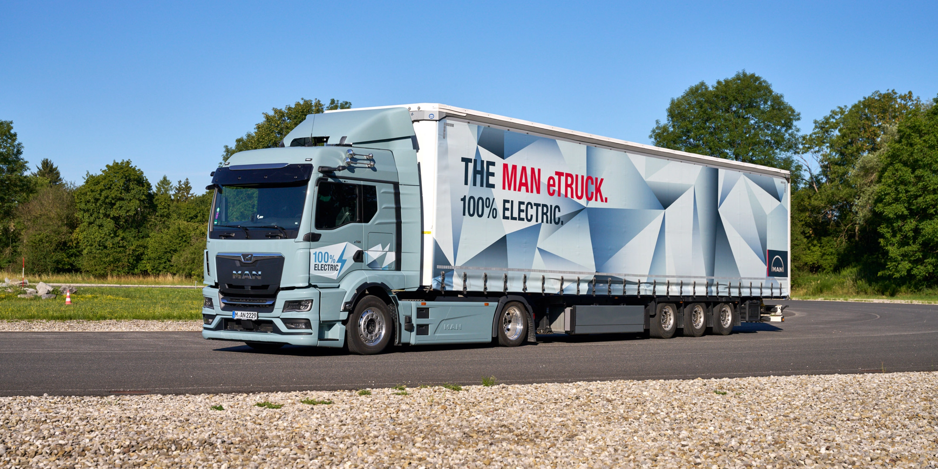 MAN truck with a trailer featuring a large graphic parked on a paved area.