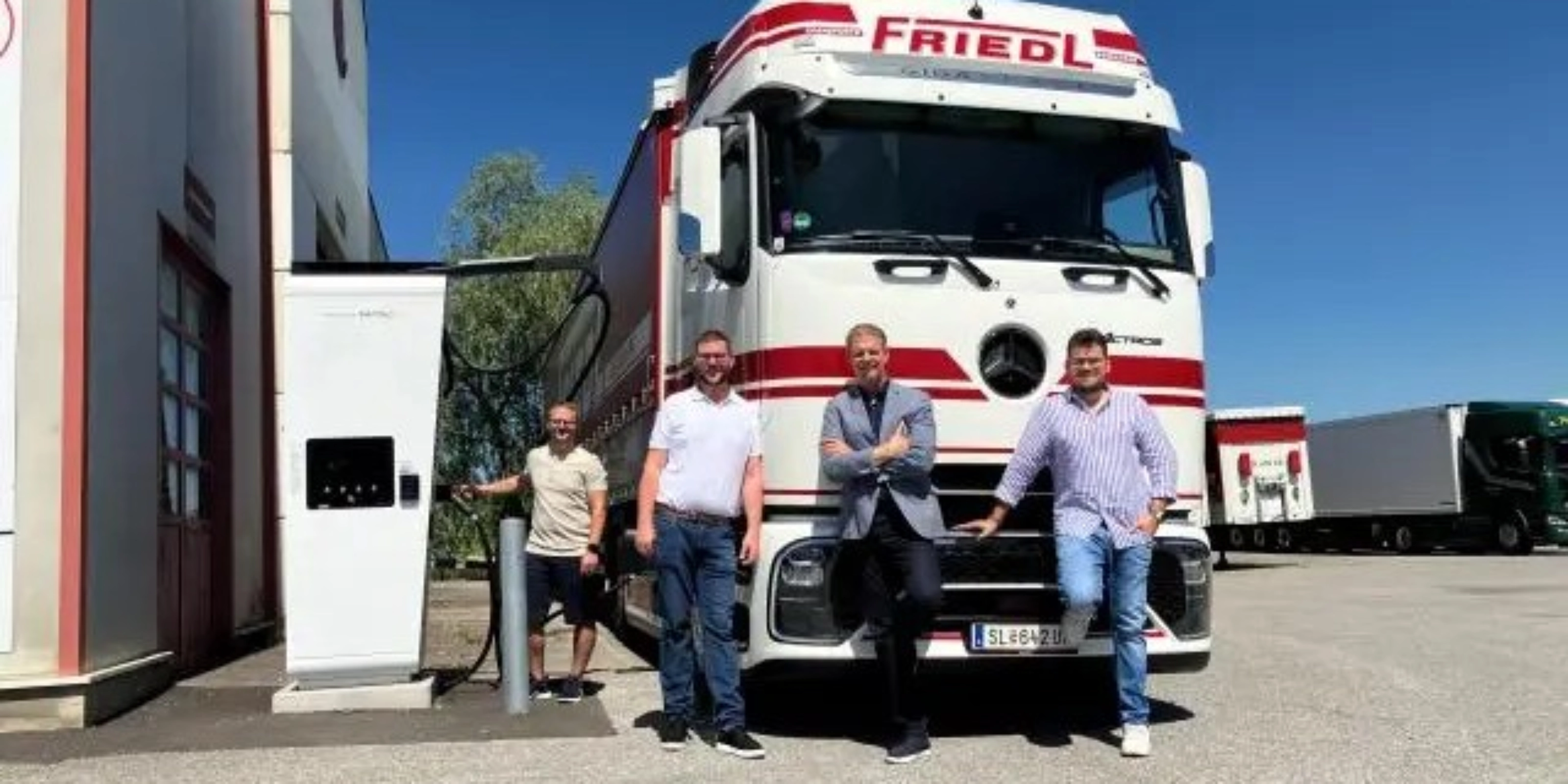 Vier Männer stehen vor einem weißen Frigel Lkw.