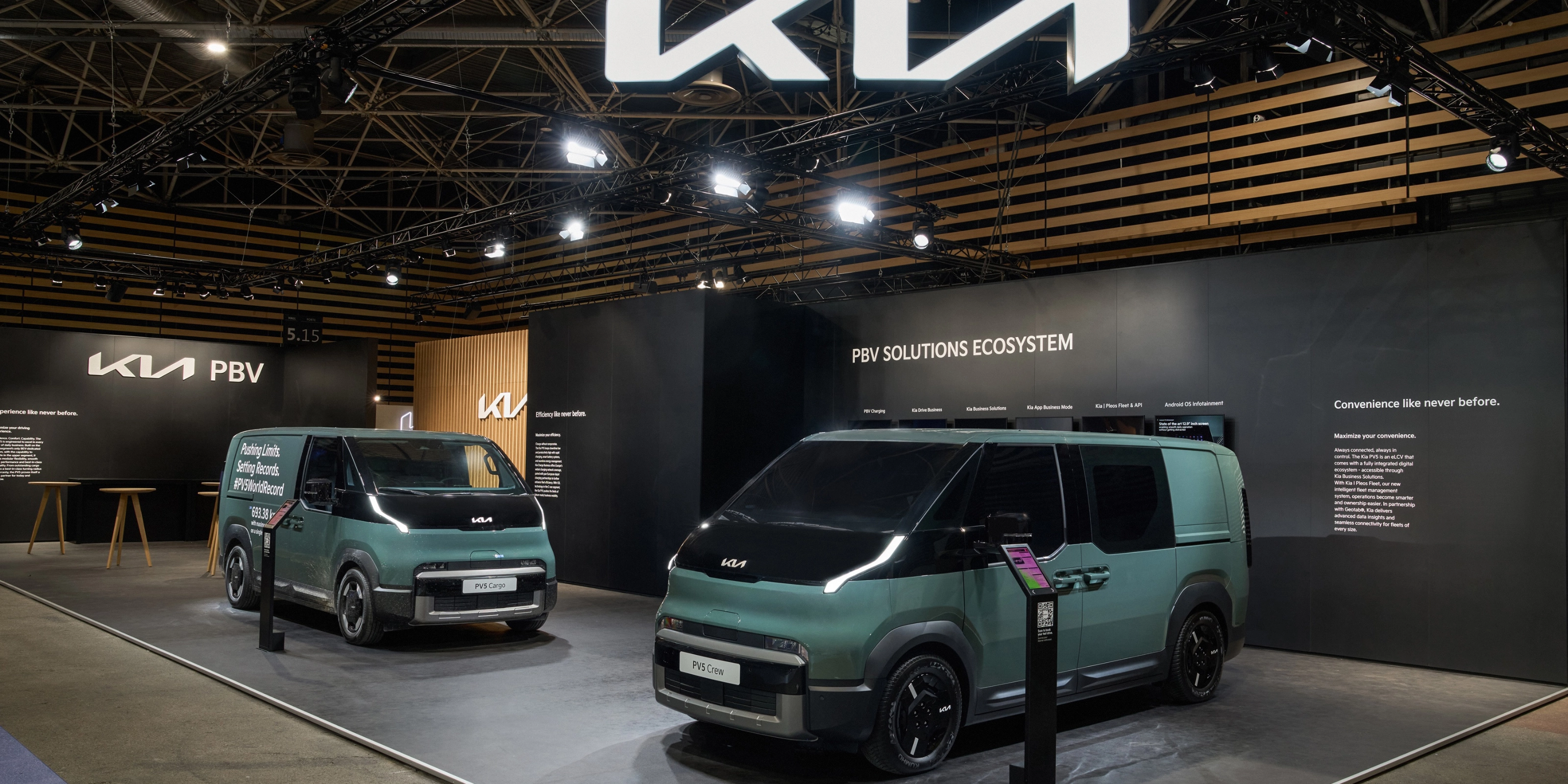Zwei grüne Kia PBV Transporter stehen auf einem Messestand mit Kia-Logo.
