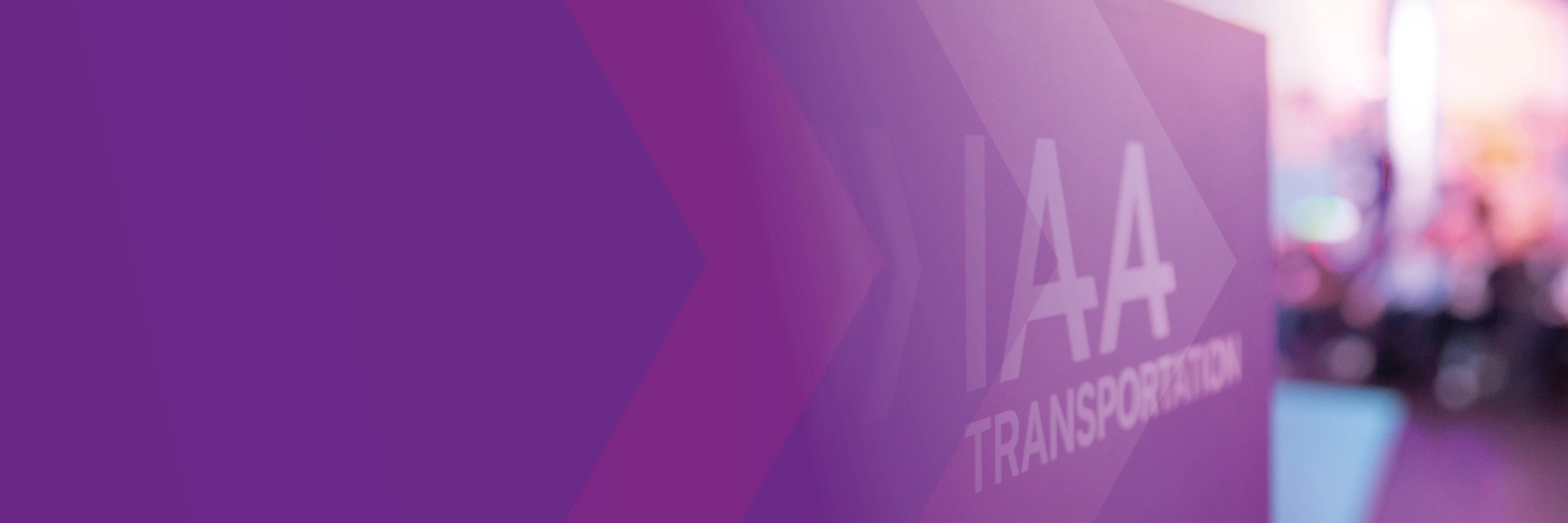 Schild mit der Aufschrift „IAA TRANSPORTATION“ auf einer Messe, lila Gestaltung im Vordergrund.