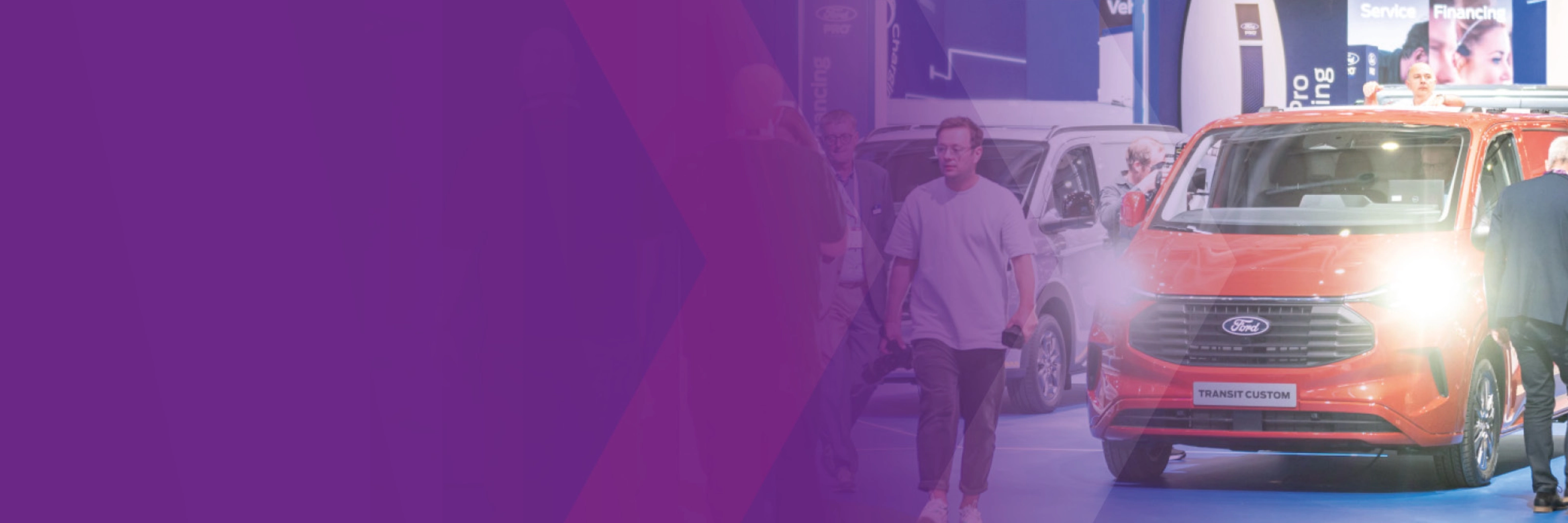 Visitors walking past a Ford Transit Custom at an IAA trade fair booth.