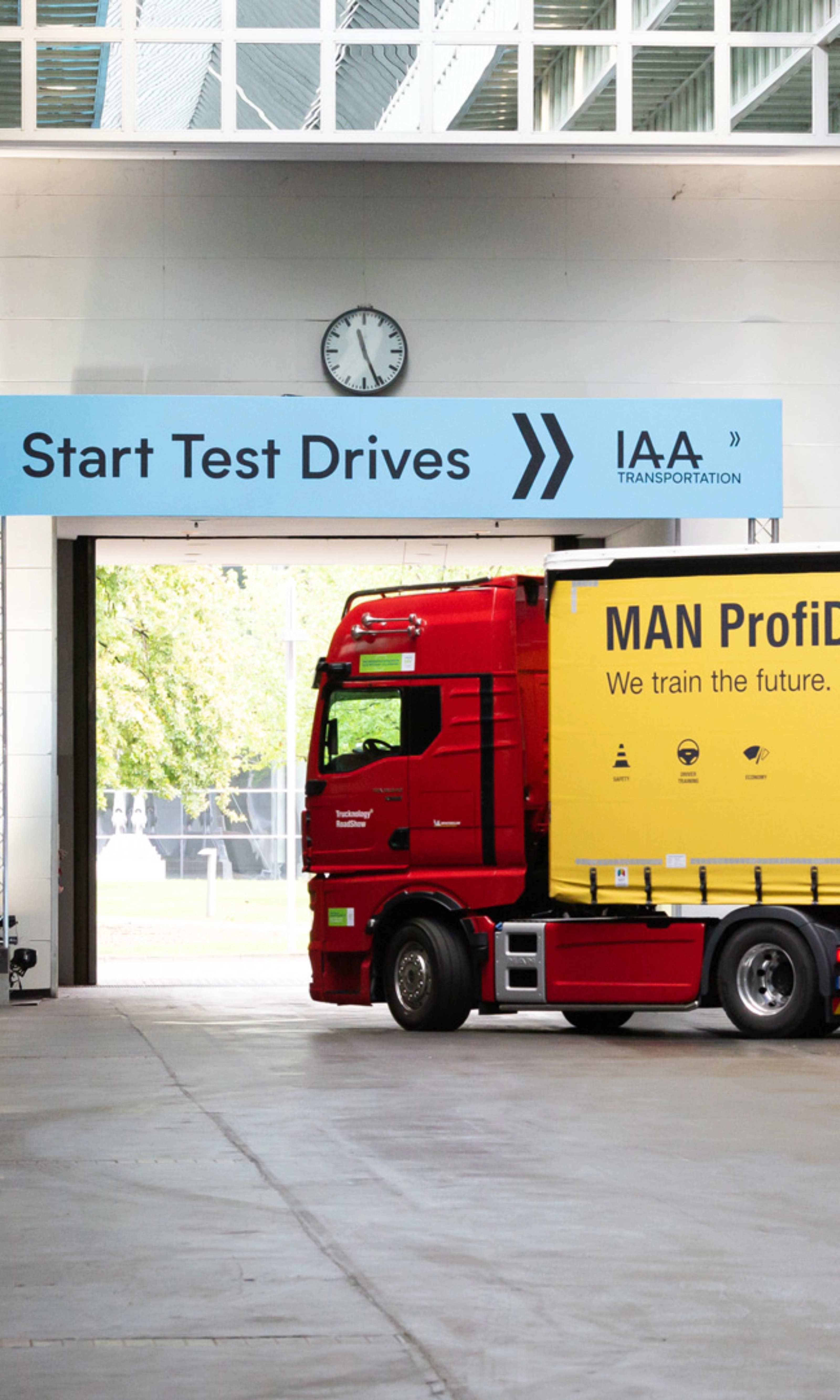 Truck with MAN ProfiDrive branding entering the IAA test‑drive start area inside a hall.