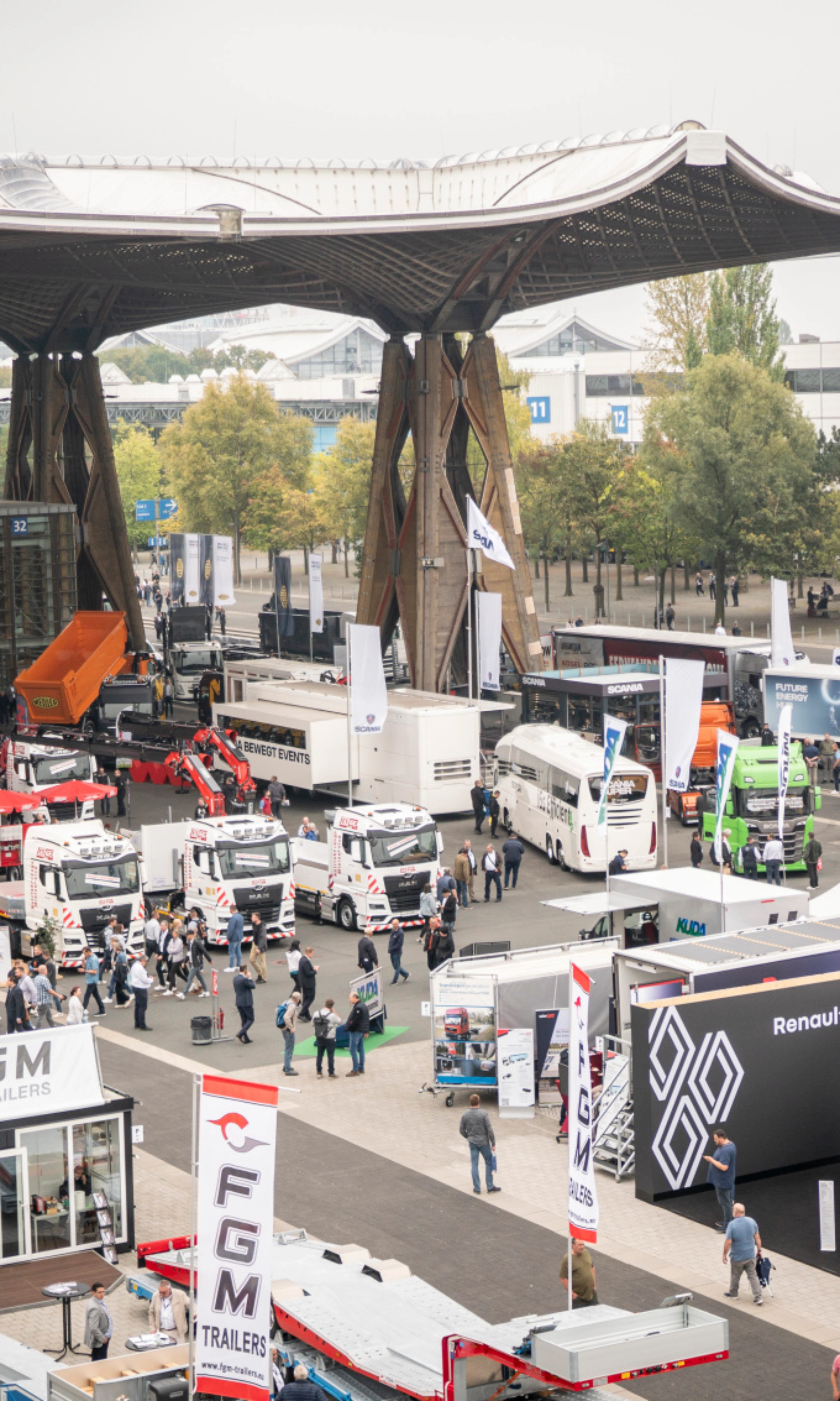 Man presenting vehicle technology on a lit-up stage at a trade fair with audience watching.