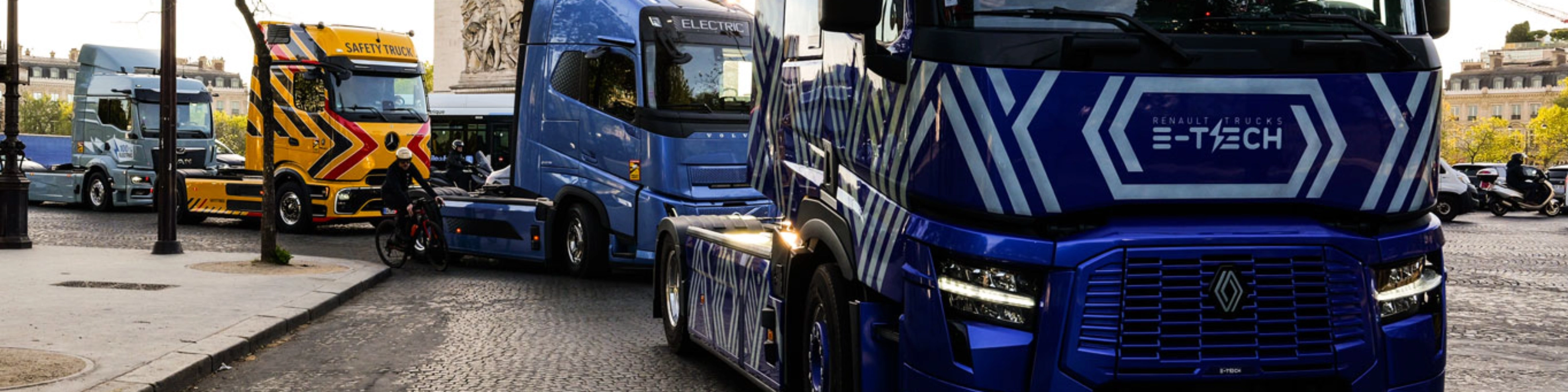 Blue electric truck driving past the Arc de Triomphe in Paris.