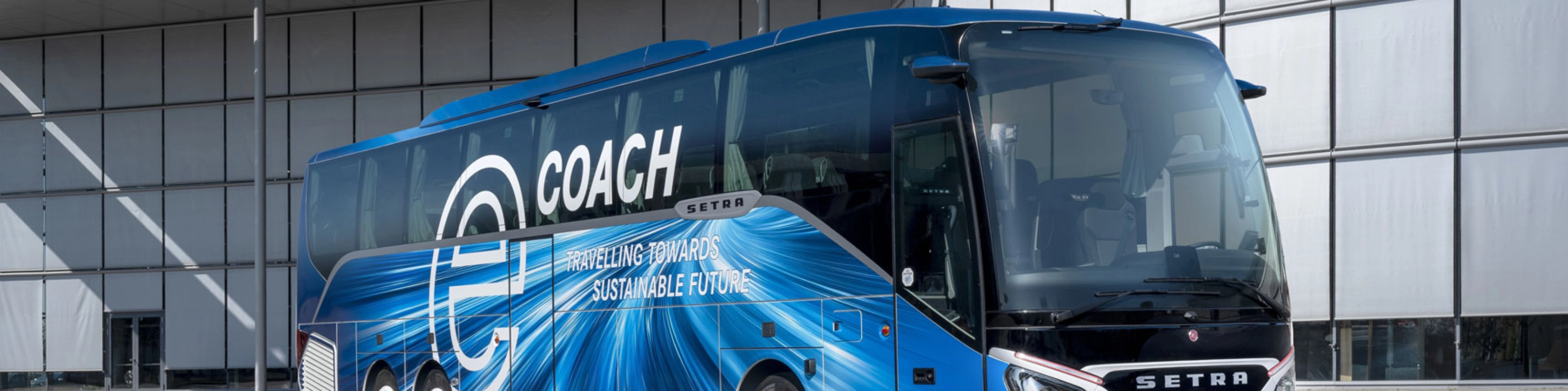 Blauer Setra-Reisebus mit Nachhaltigkeits-Slogan vor modernem Gebäude.
