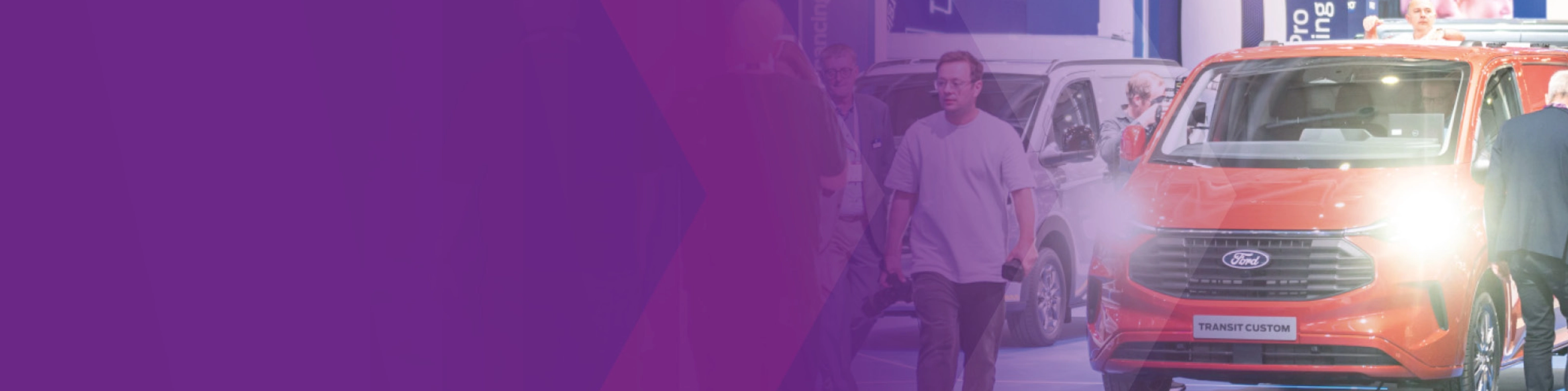 Visitors walking past a Ford Transit Custom at an IAA trade fair booth.