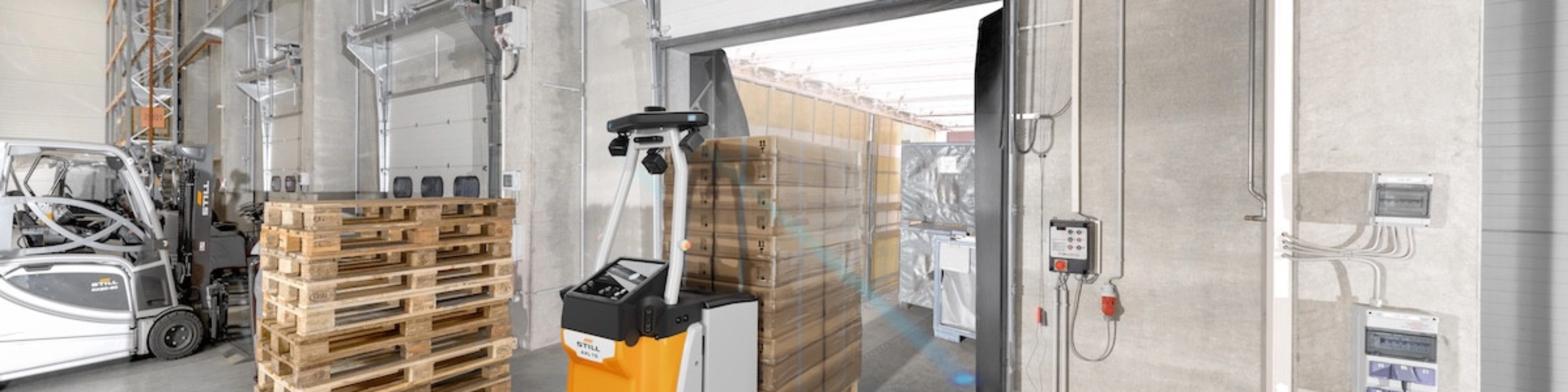 Autonomous mobile robot transporting goods at an industrial loading gate.