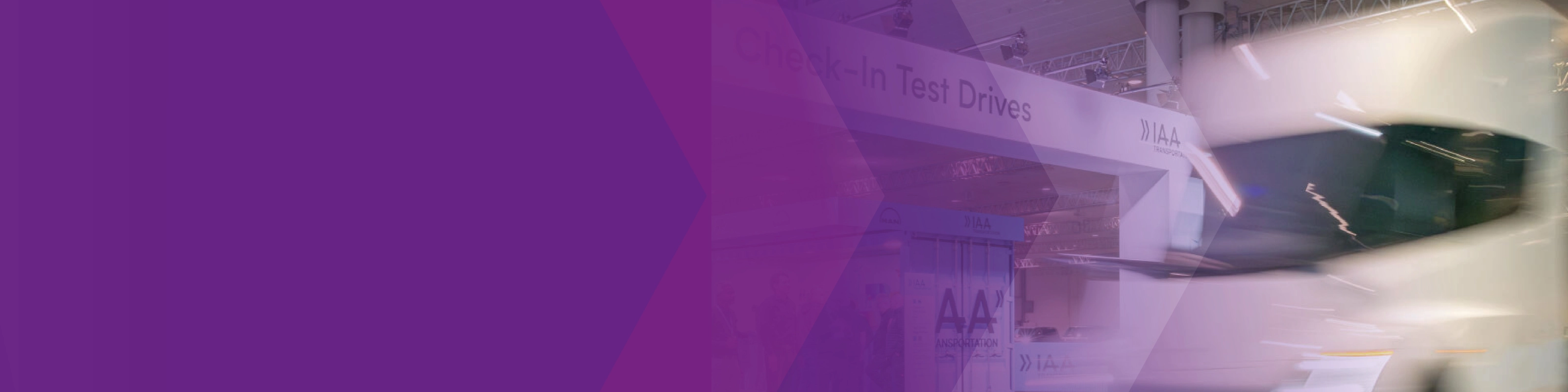 Blurred white truck at the IAA test drive area with a purple graphic overlay.