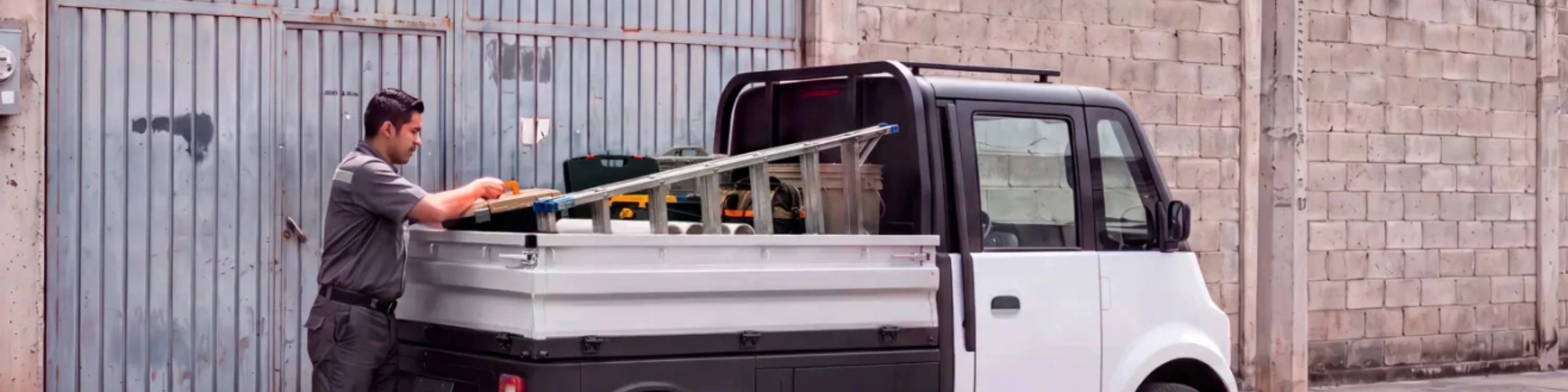 Compact Olinia utility vehicle being loaded at the roadside.