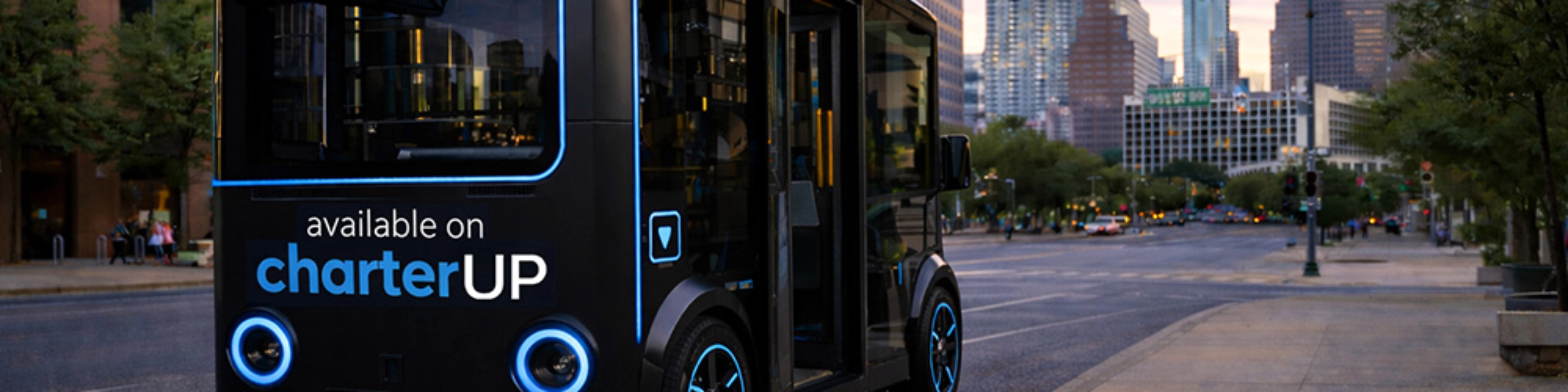 Small black electric shuttle bus with CharterUP logo in city street.