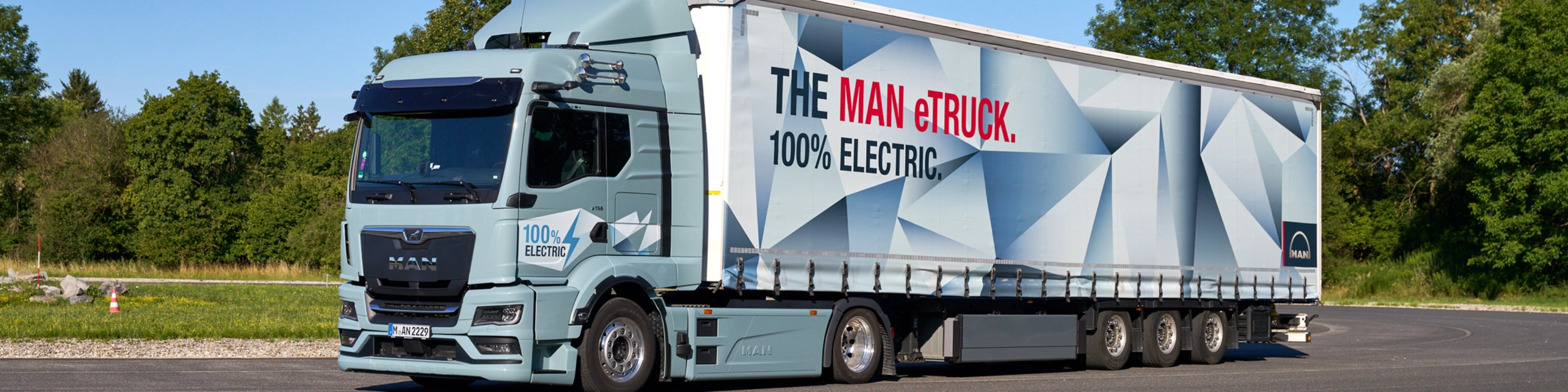 MAN truck with a trailer featuring a large graphic parked on a paved area.