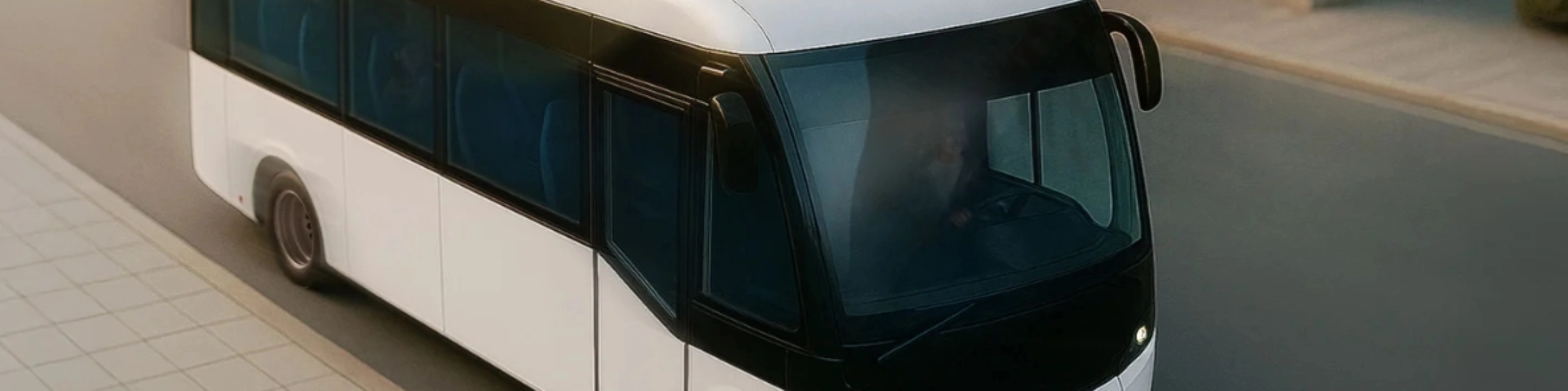 Small white autonomous shuttle bus driving on a city street, viewed from above.