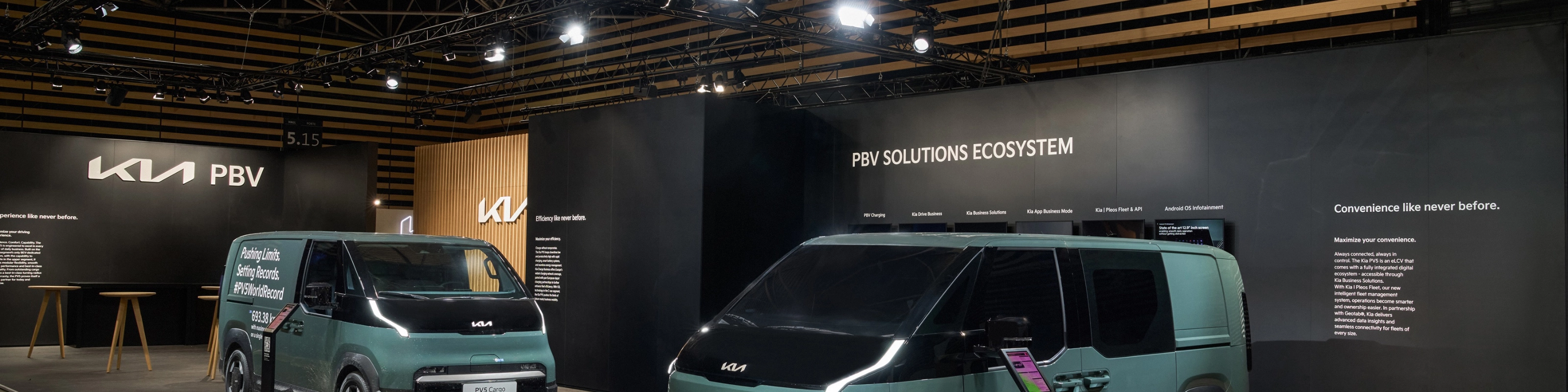 Zwei grüne Kia PBV Transporter stehen auf einem Messestand mit Kia-Logo.