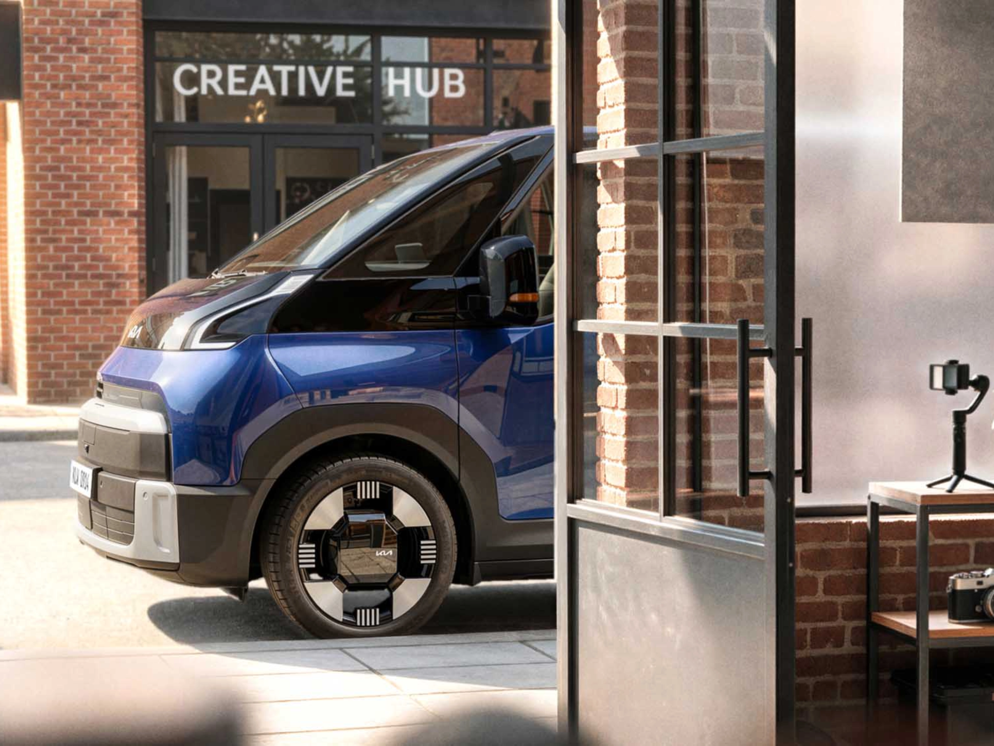 Blauer Kia PV7 vor einem Creative Hub.