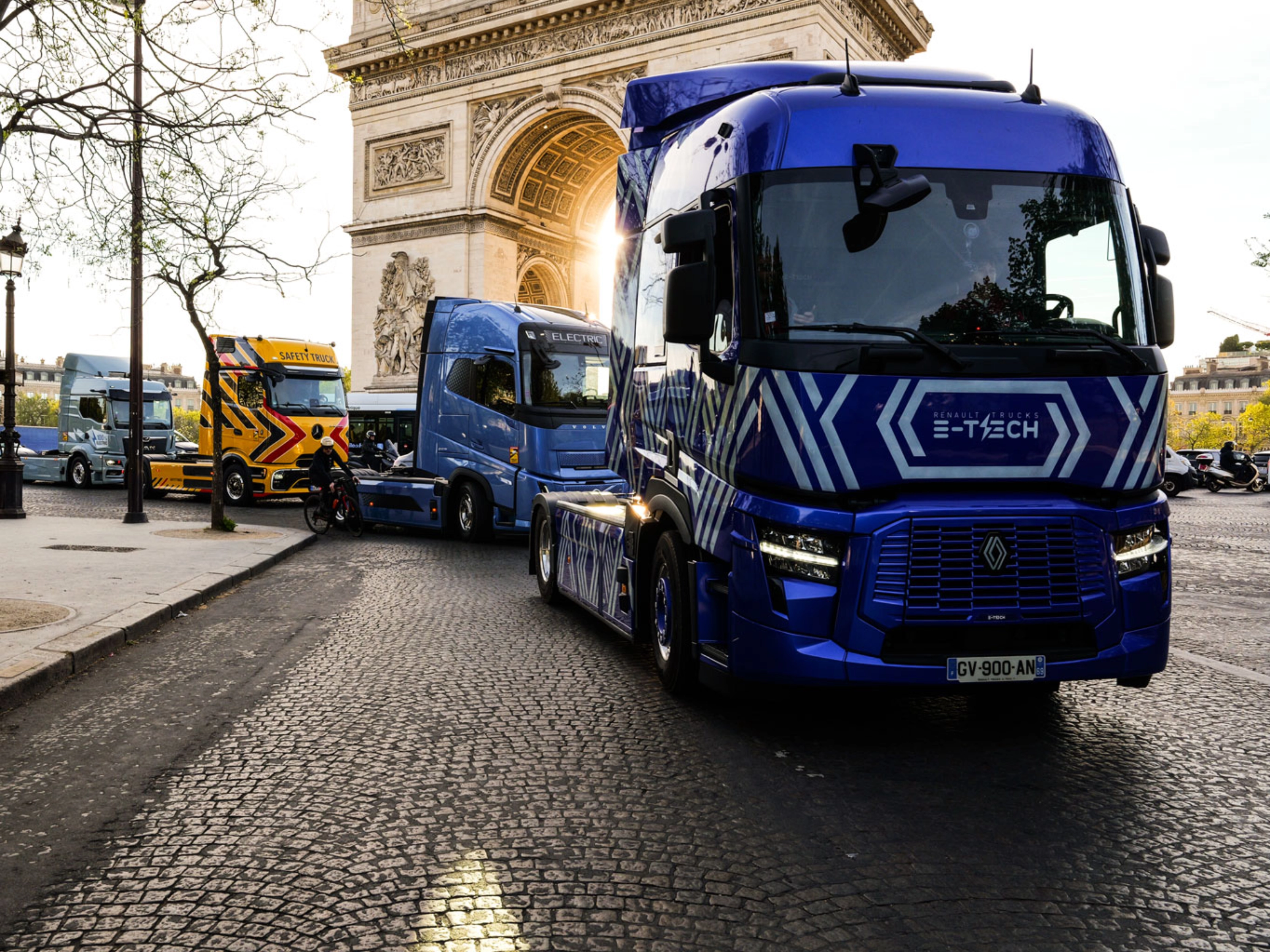 Blue electric truck driving past the Arc de Triomphe in Paris.