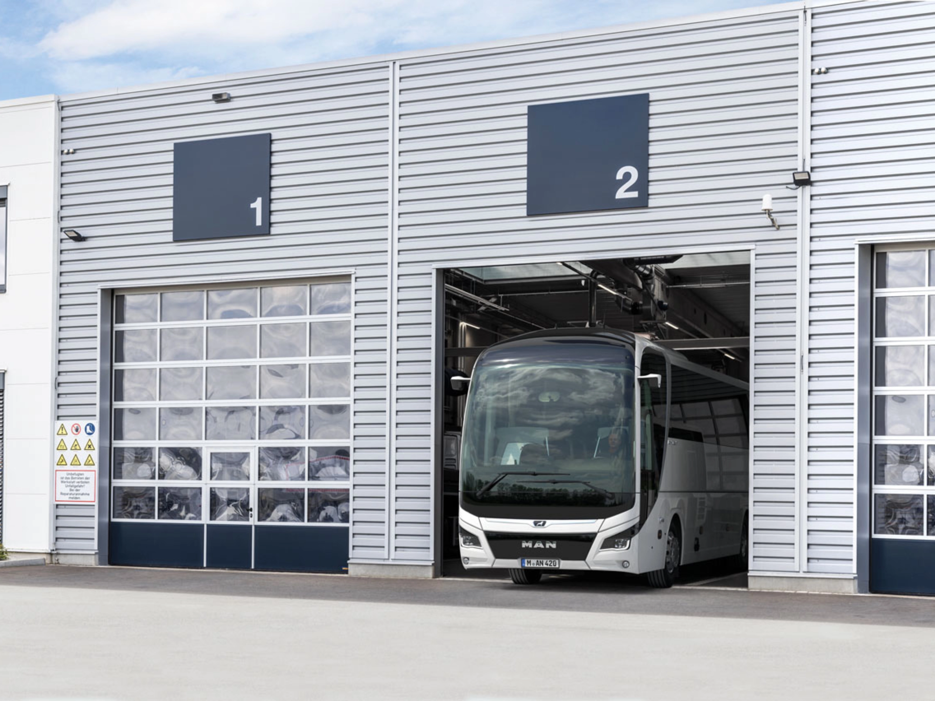 Ein Bus steht in einer nummerierten Garage eines modernen Betriebsgebäudes.