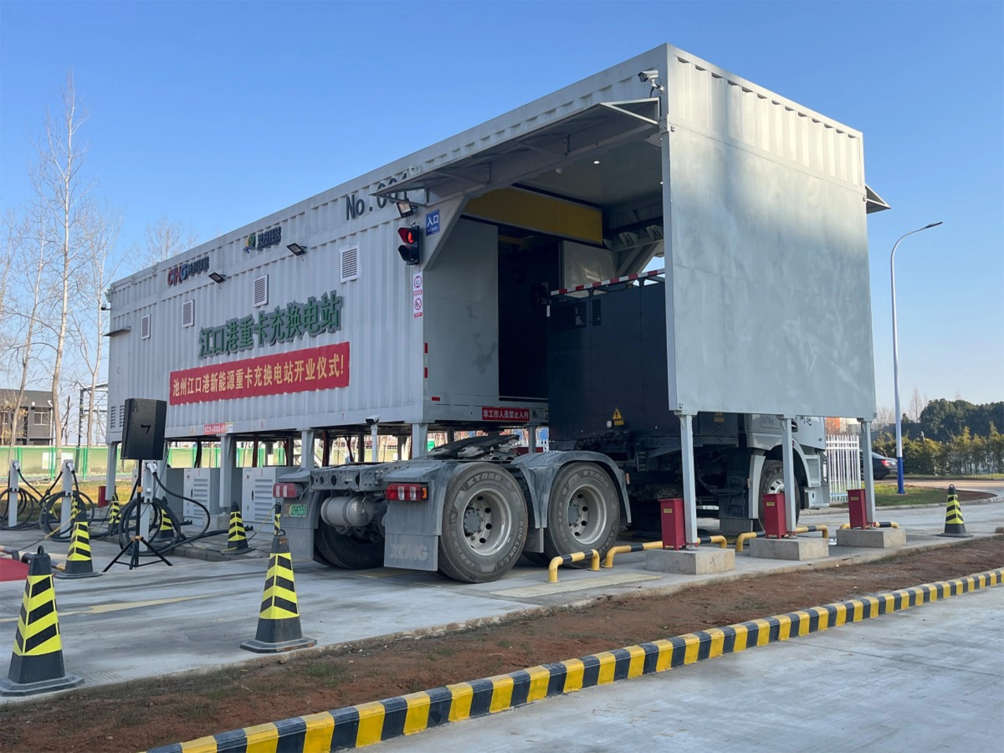 Truck at battery swap station with container module in industrial area.