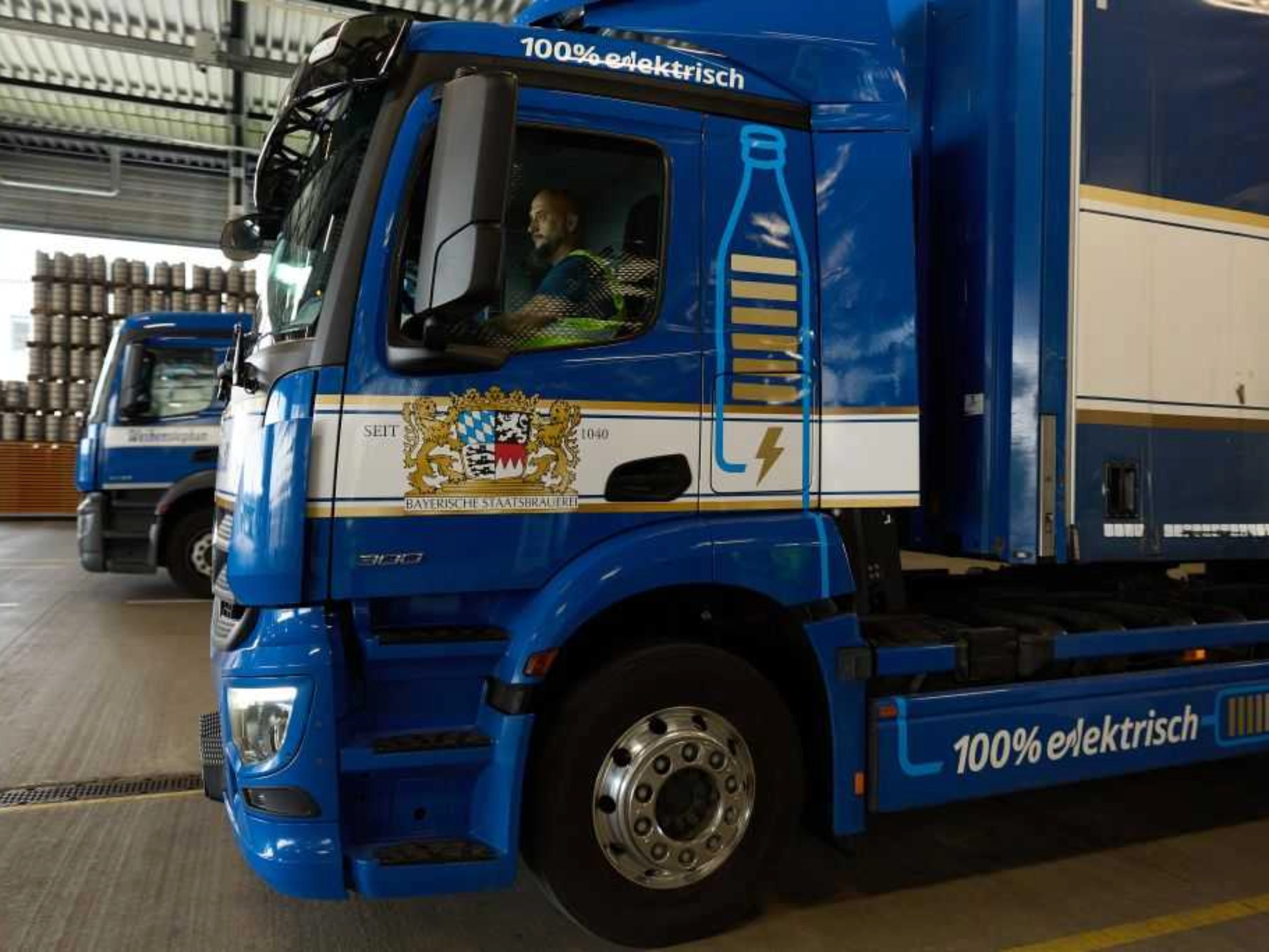 Lastwagen steht in einer Logistikhalle, Fahrer sitzt im Führerhaus.