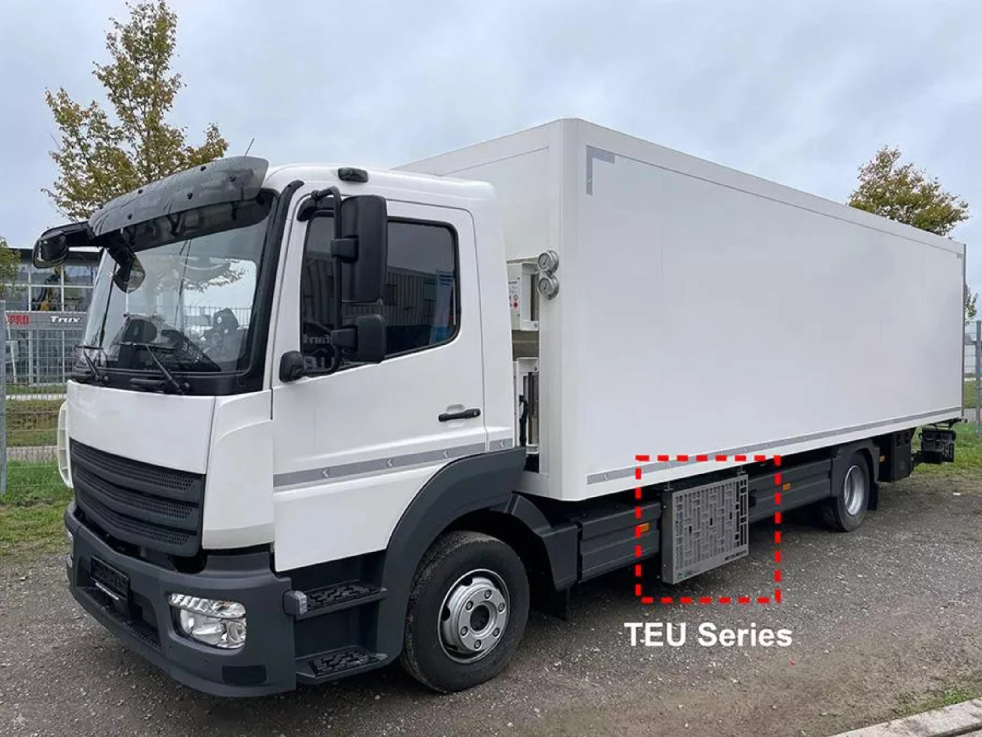 Weißer Mitsubishi Heavy Industries Koffer-Lkw mit seitlich montierten TEU-Boxen.