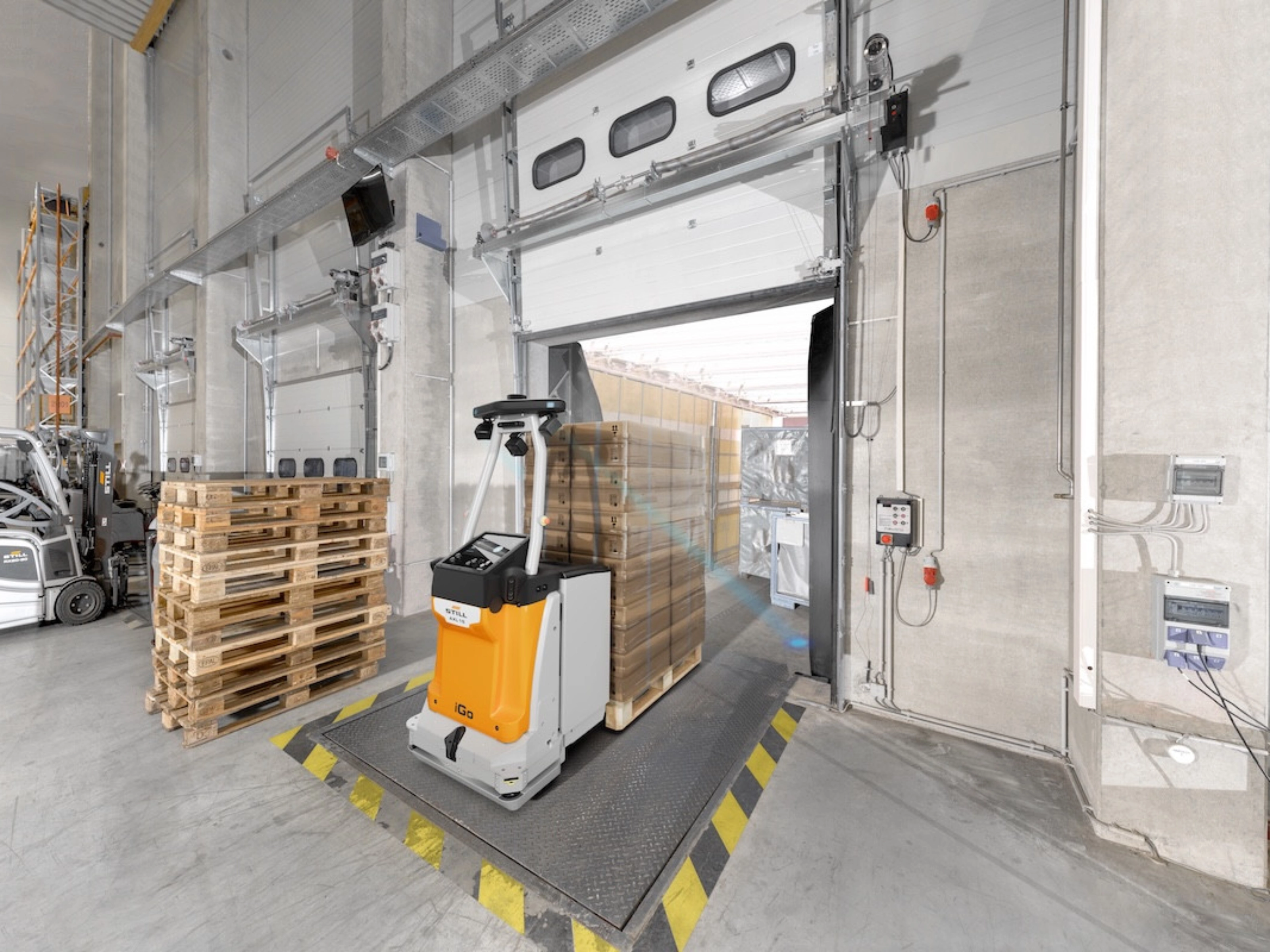 Autonomous mobile robot transporting goods at an industrial loading gate.