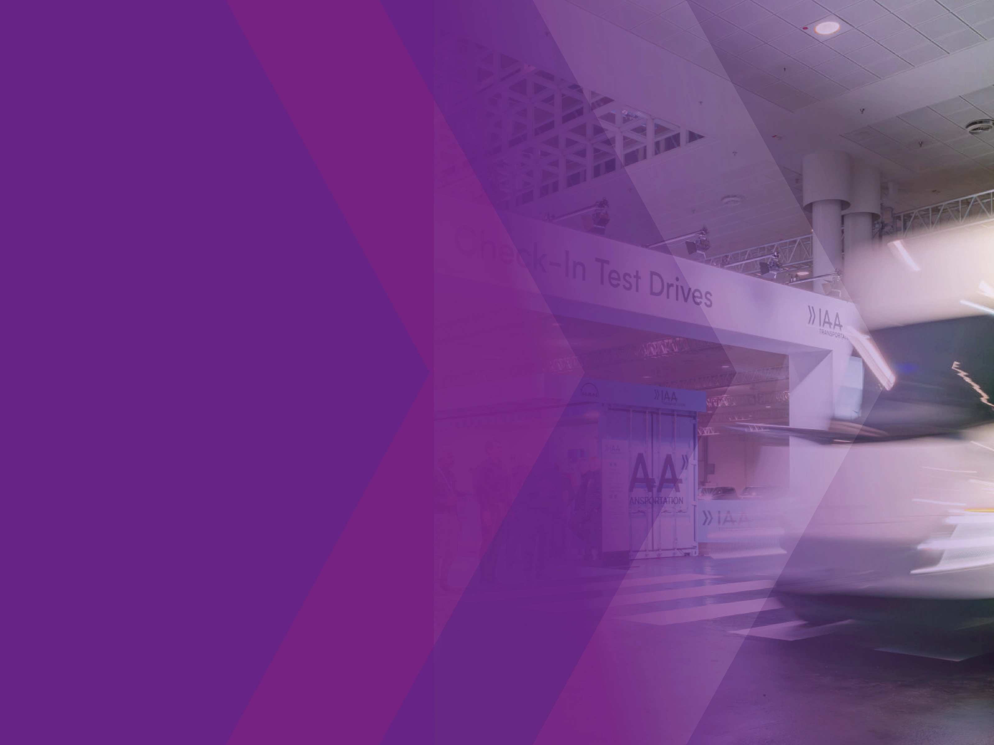 Blurred white truck at the IAA test drive area with a purple graphic overlay.