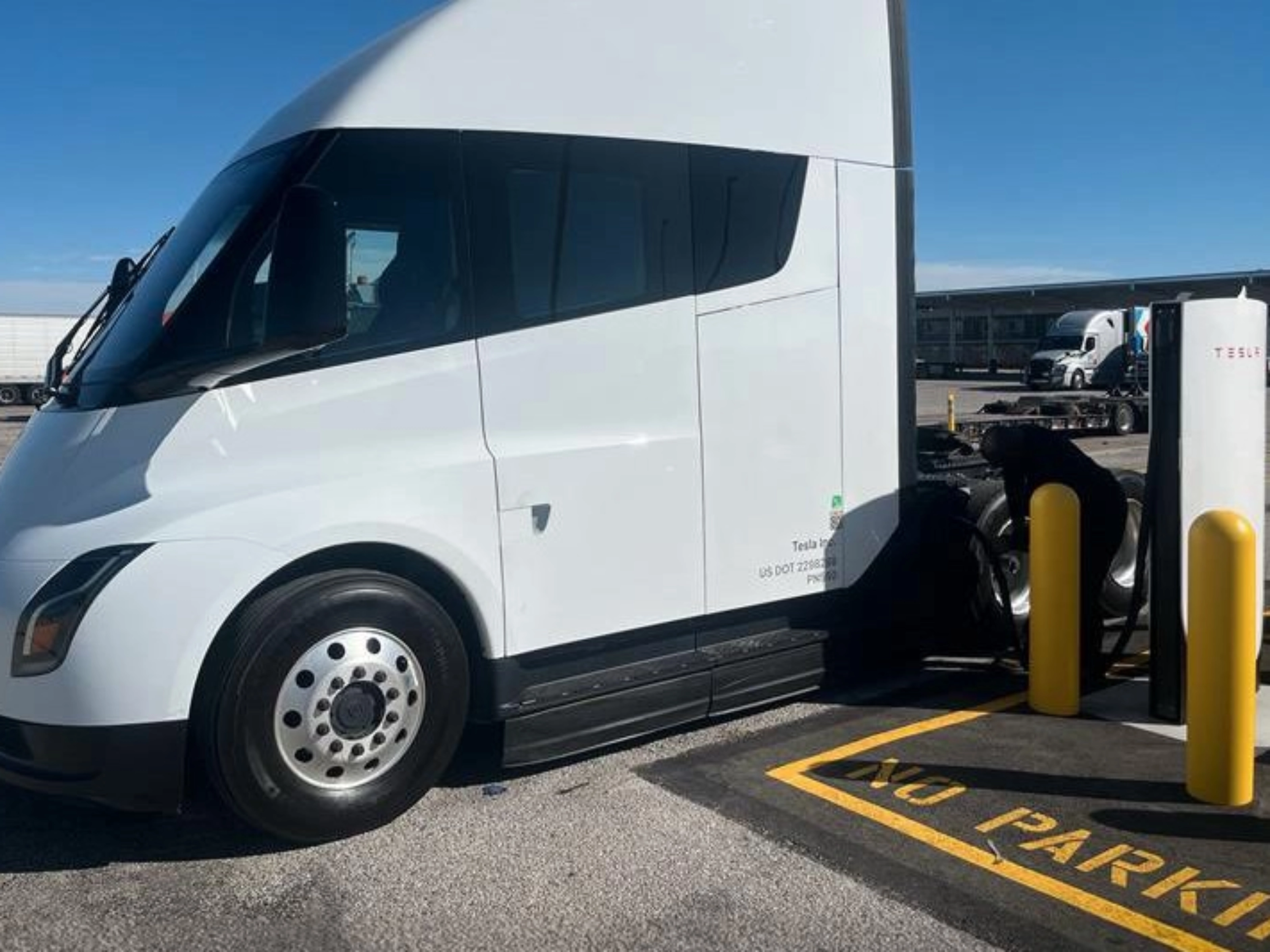 White Tesla Semi charging at a Tesla charging station.