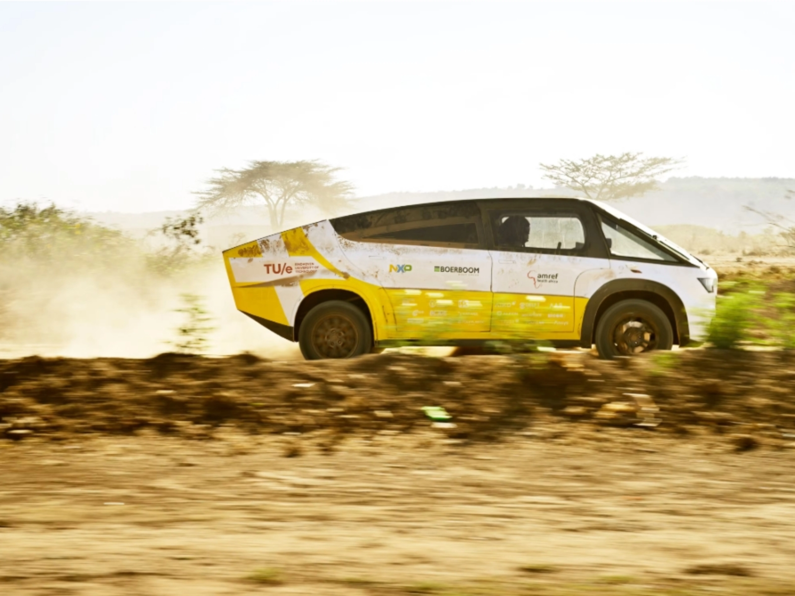 Fahrzeug des Solar Team Eindhoven fährt auf einer staubigen unbefestigten Straße.