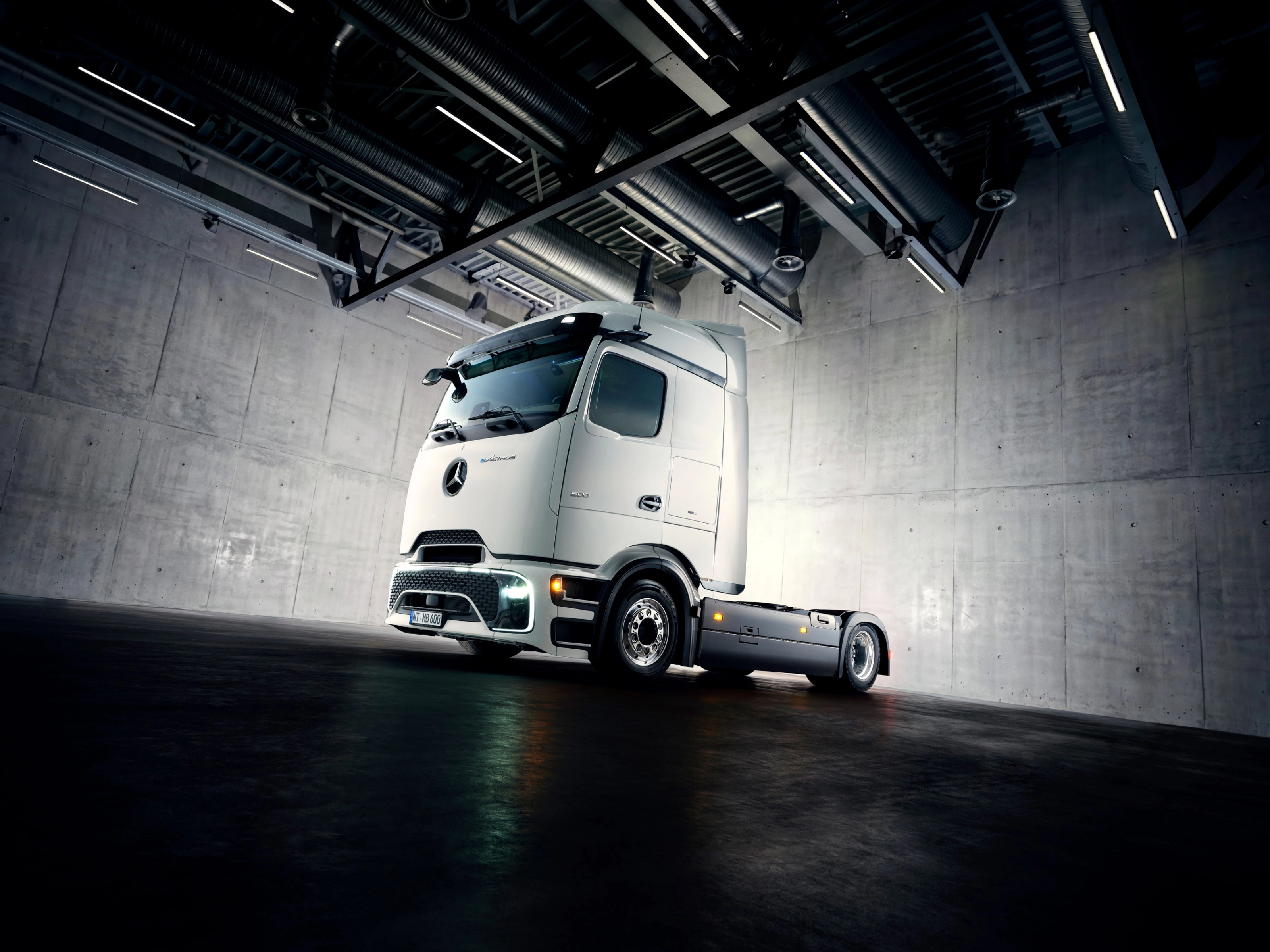 Autonomes Lkw-Fahrgestell in Industriehalle unter Scheinwerfern.