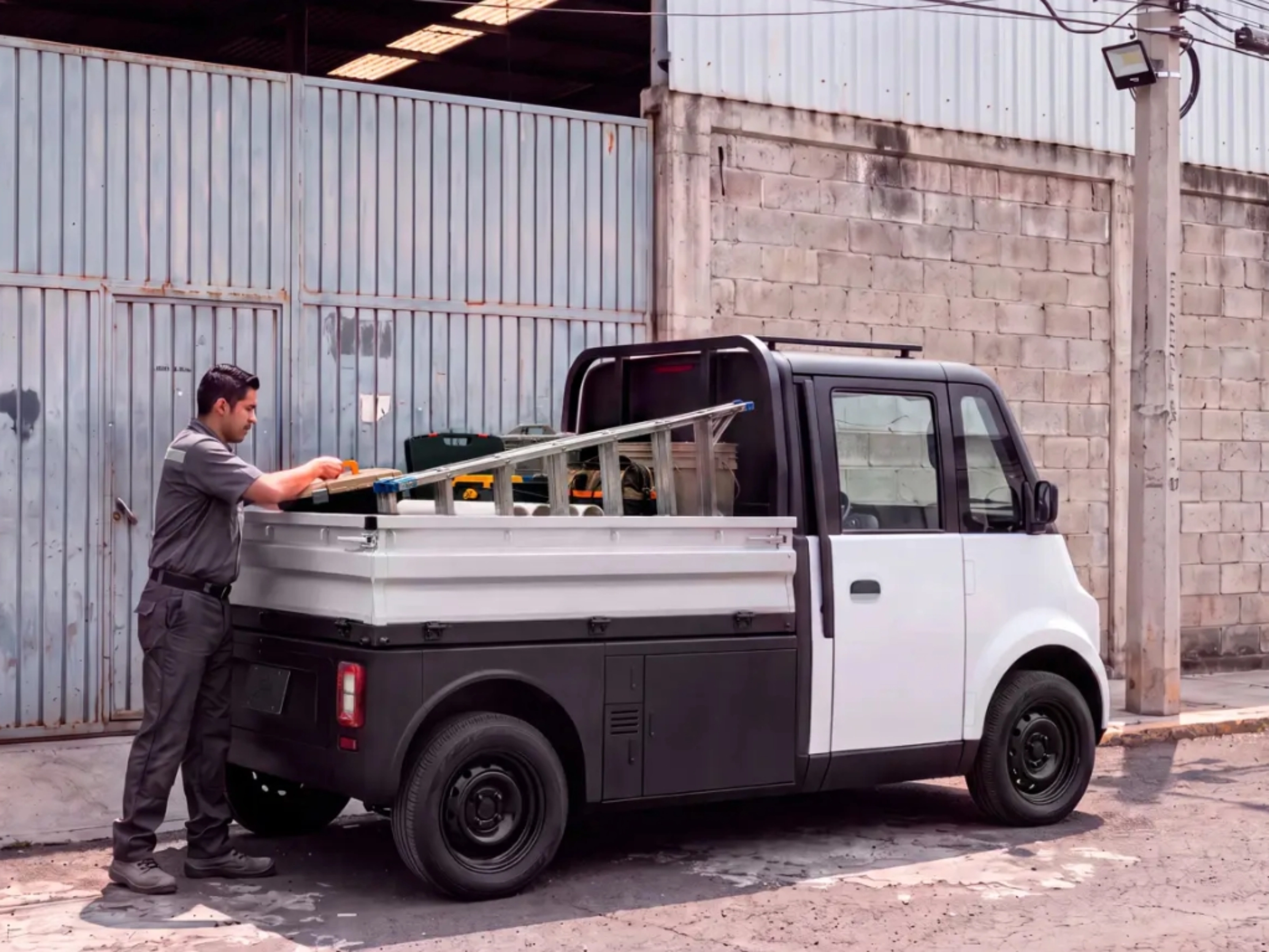 Compact Olinia utility vehicle being loaded at the roadside.