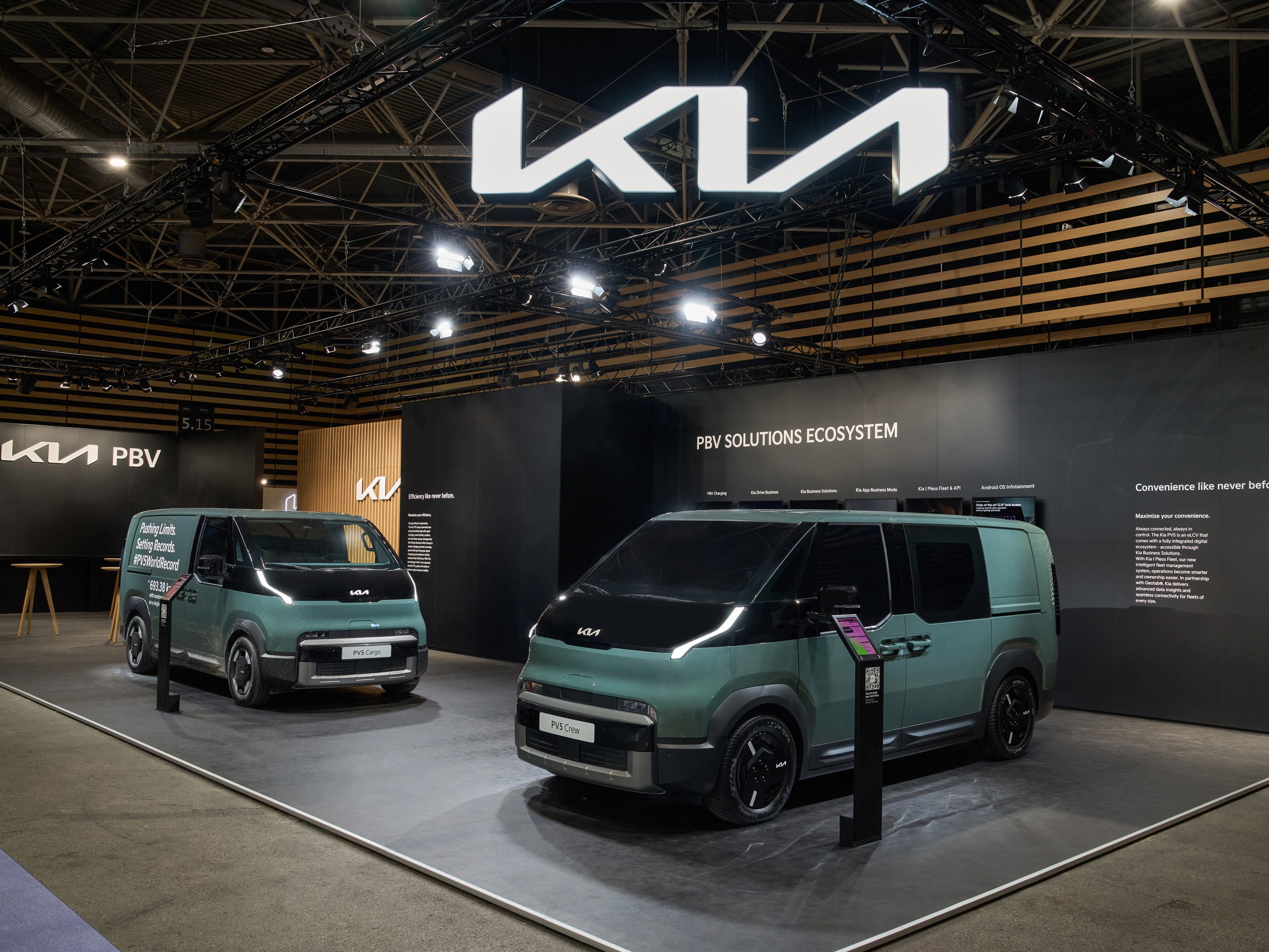 Zwei grüne Kia PBV Transporter stehen auf einem Messestand mit Kia-Logo.