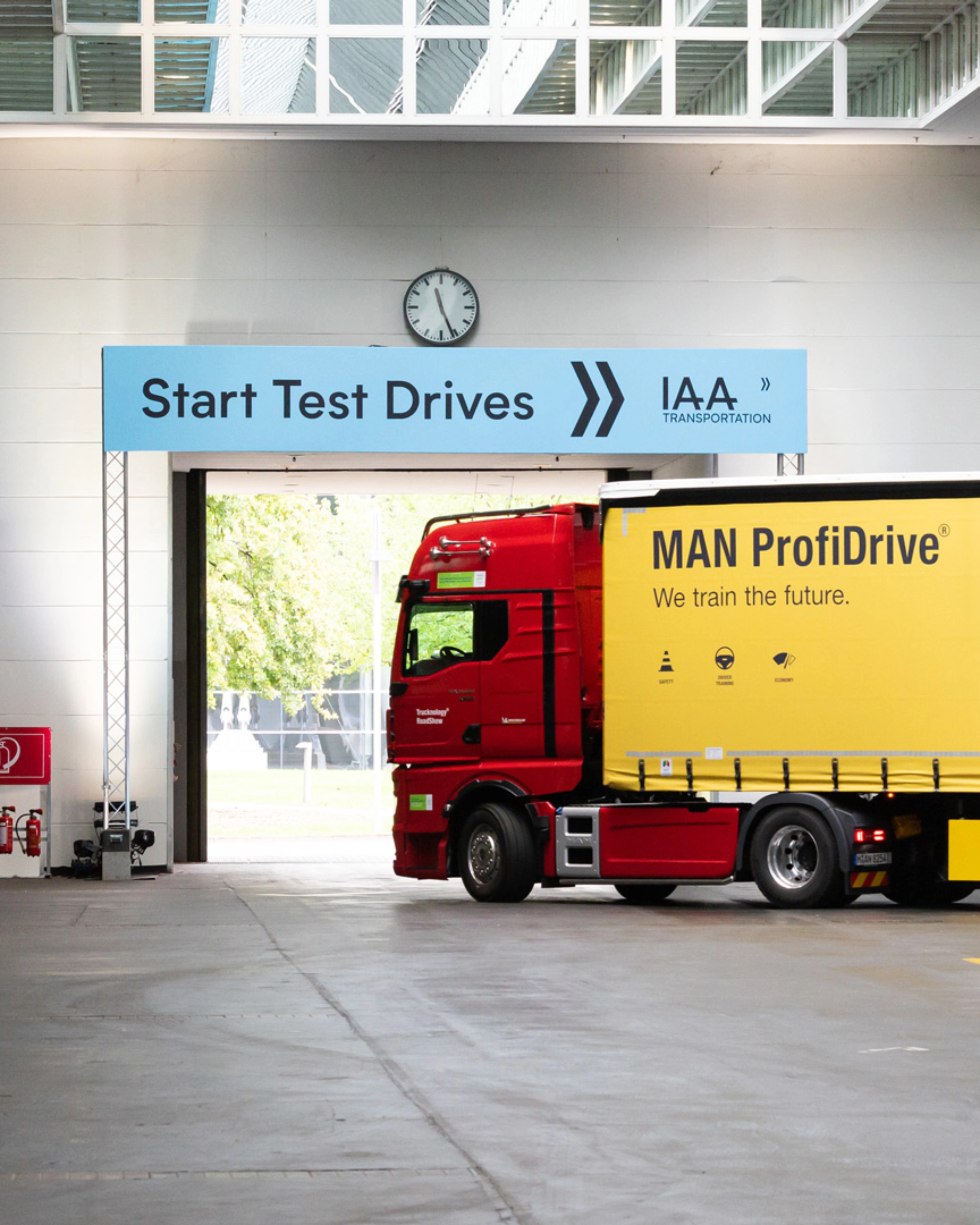 Truck with MAN ProfiDrive branding entering the IAA test‑drive start area inside a hall.
