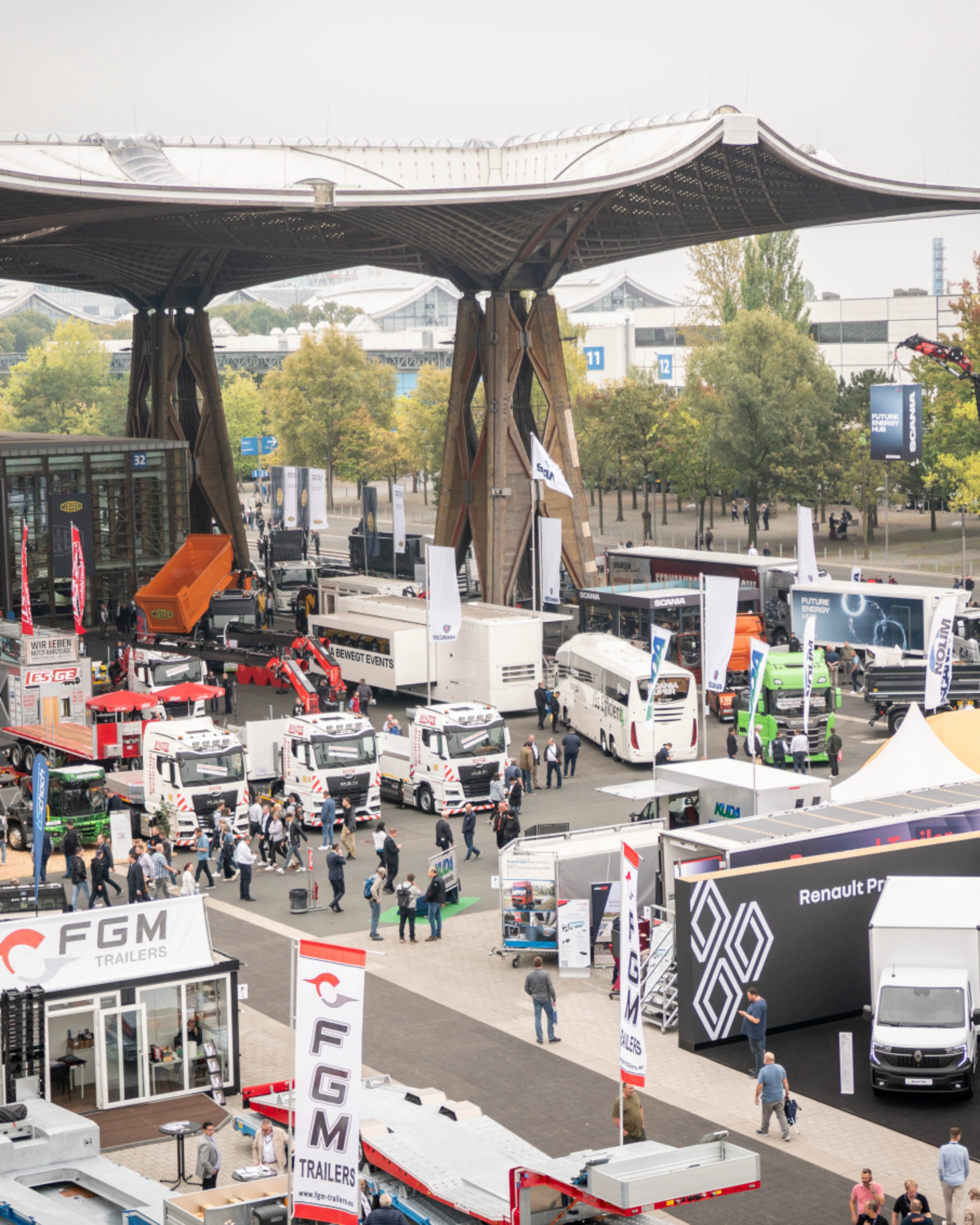 Man presenting vehicle technology on a lit-up stage at a trade fair with audience watching.