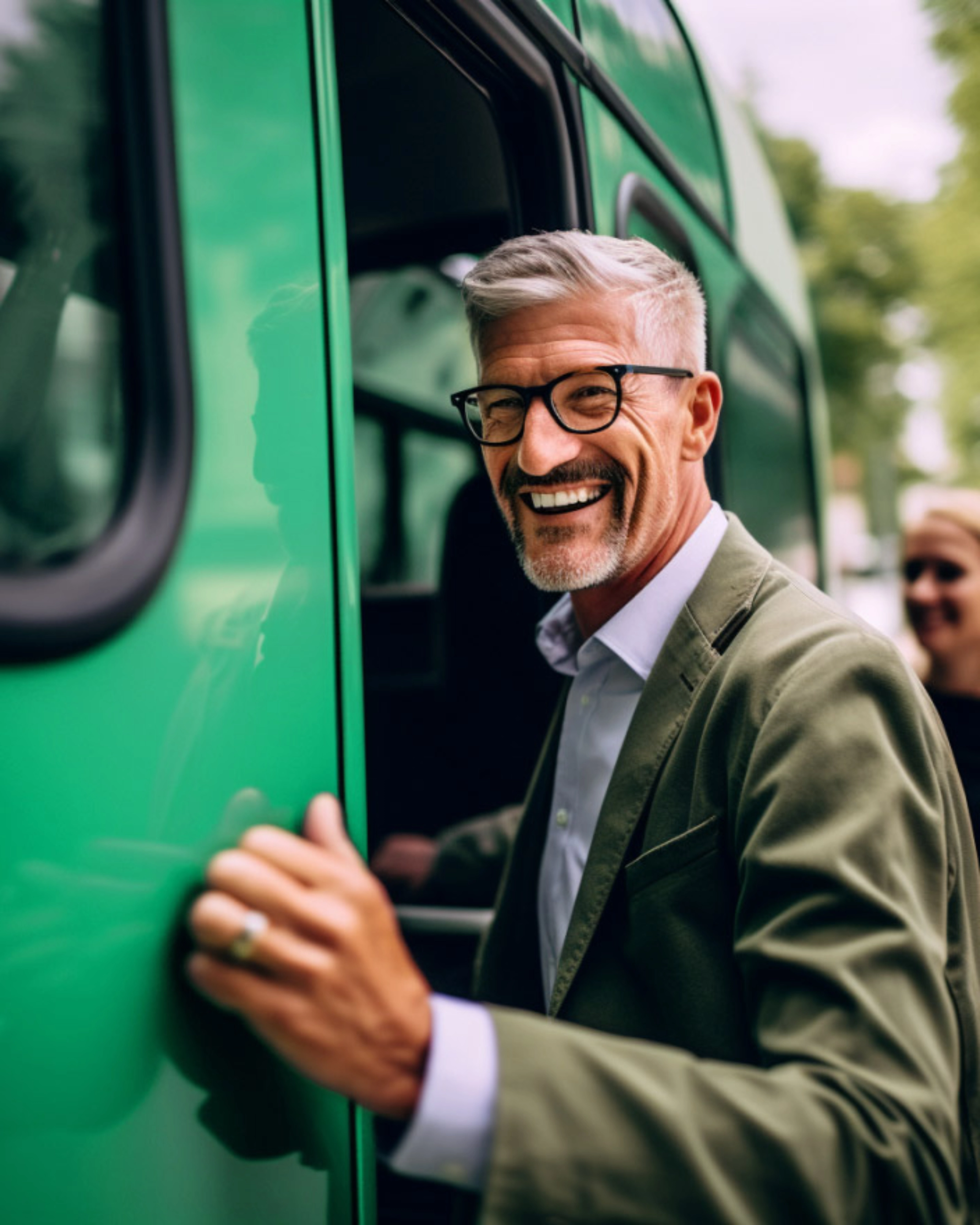 Smiling man with glasses boarding a green bus outdoors.