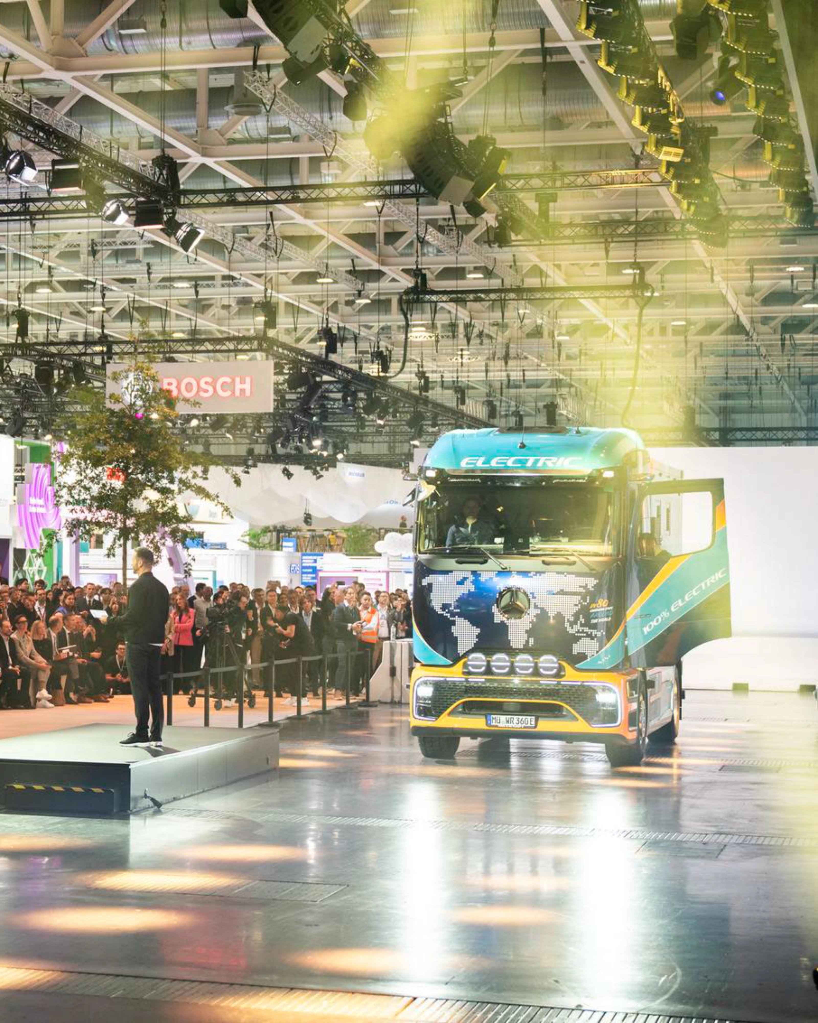 Lkw fährt in einer Messehalle an einem großen Publikum vorbei.