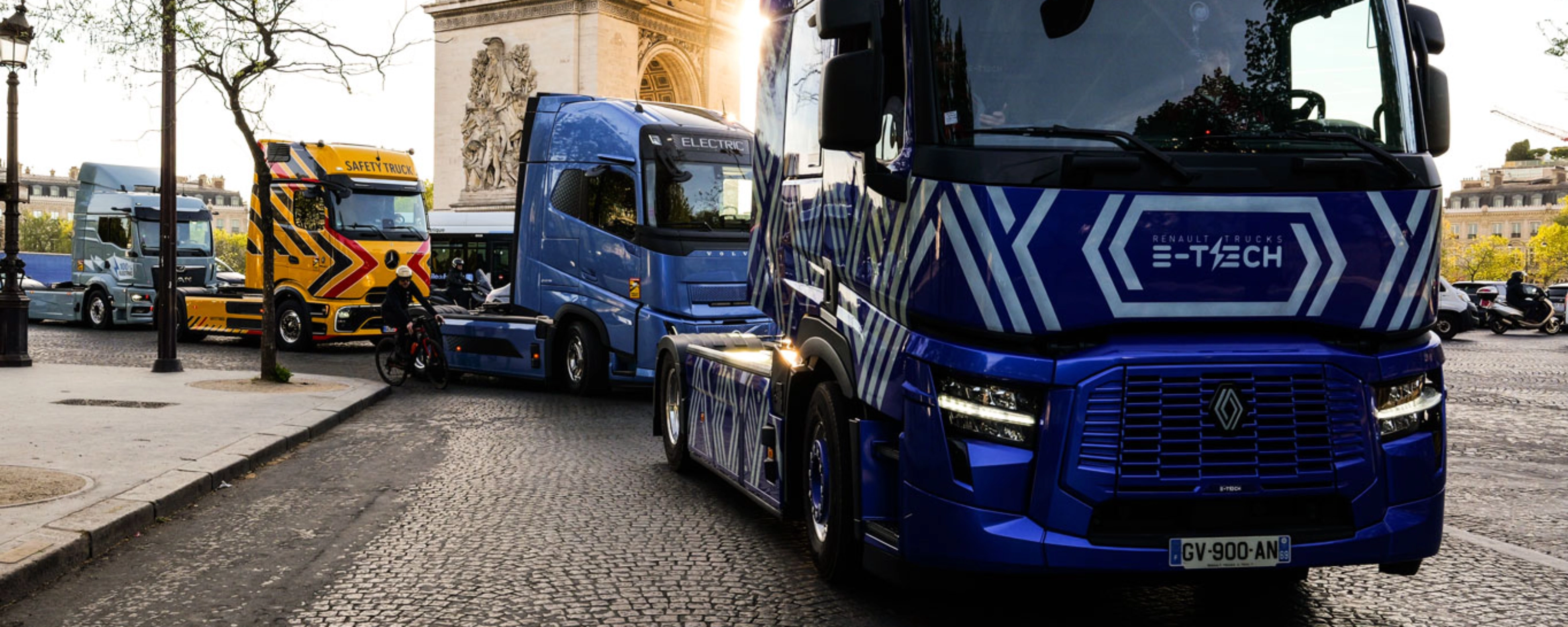Blue electric truck driving past the Arc de Triomphe in Paris.
