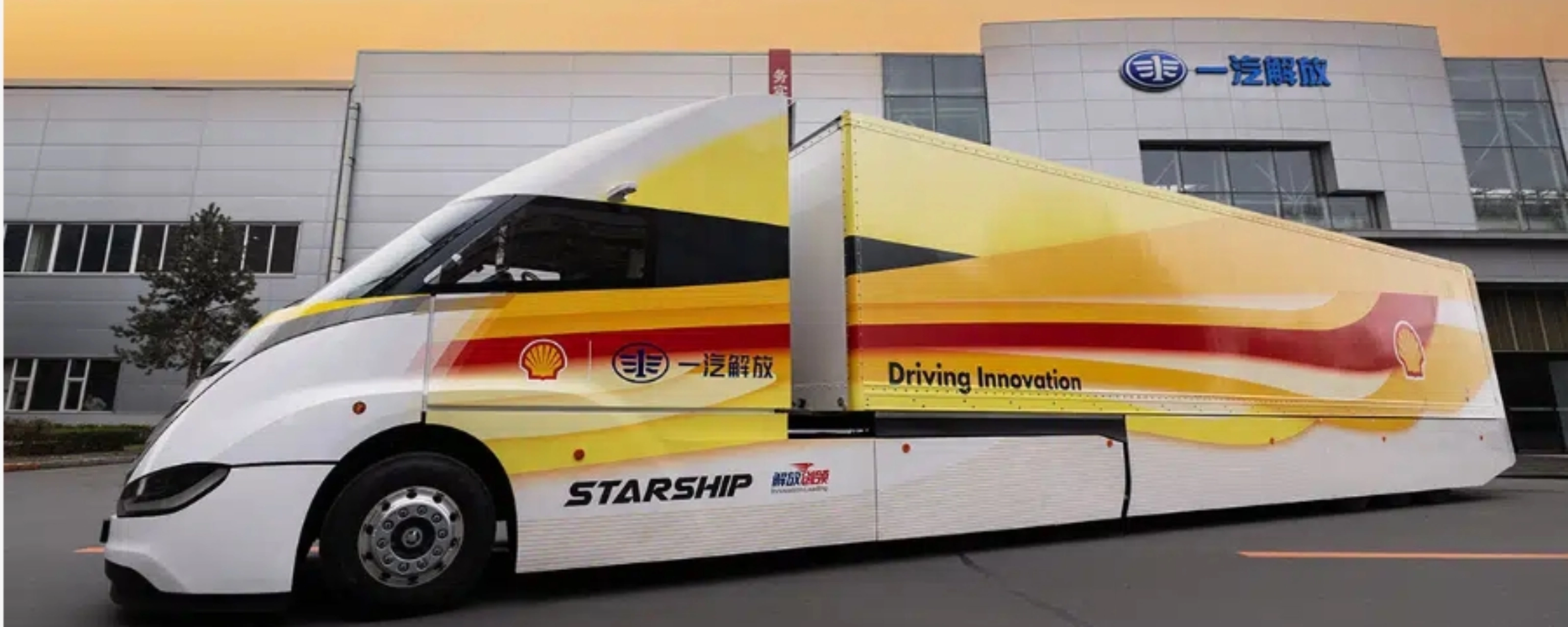 Weißer STARSHIP-Bus mit roten und gelben Streifen vor einem Industriegebäude bei Sonnenuntergang.